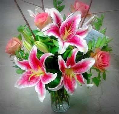Bouquet of pink lilies and roses in a clear glass vase