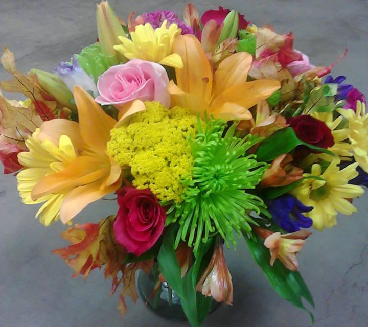 Colorful mixed bouquet with roses, lilies, and daisies in a glass vase