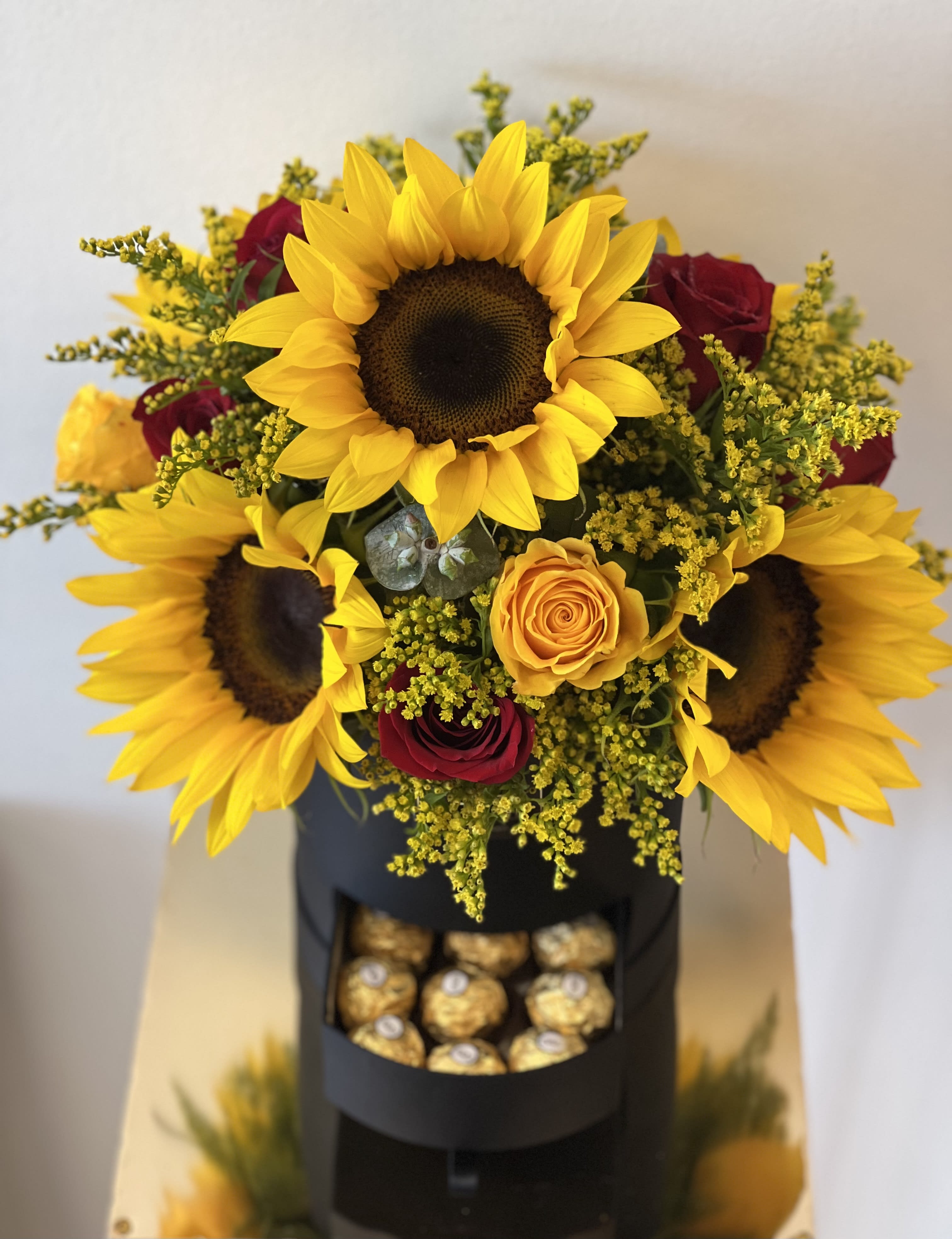 Bouquet of sunflowers and red roses with a box of chocolates