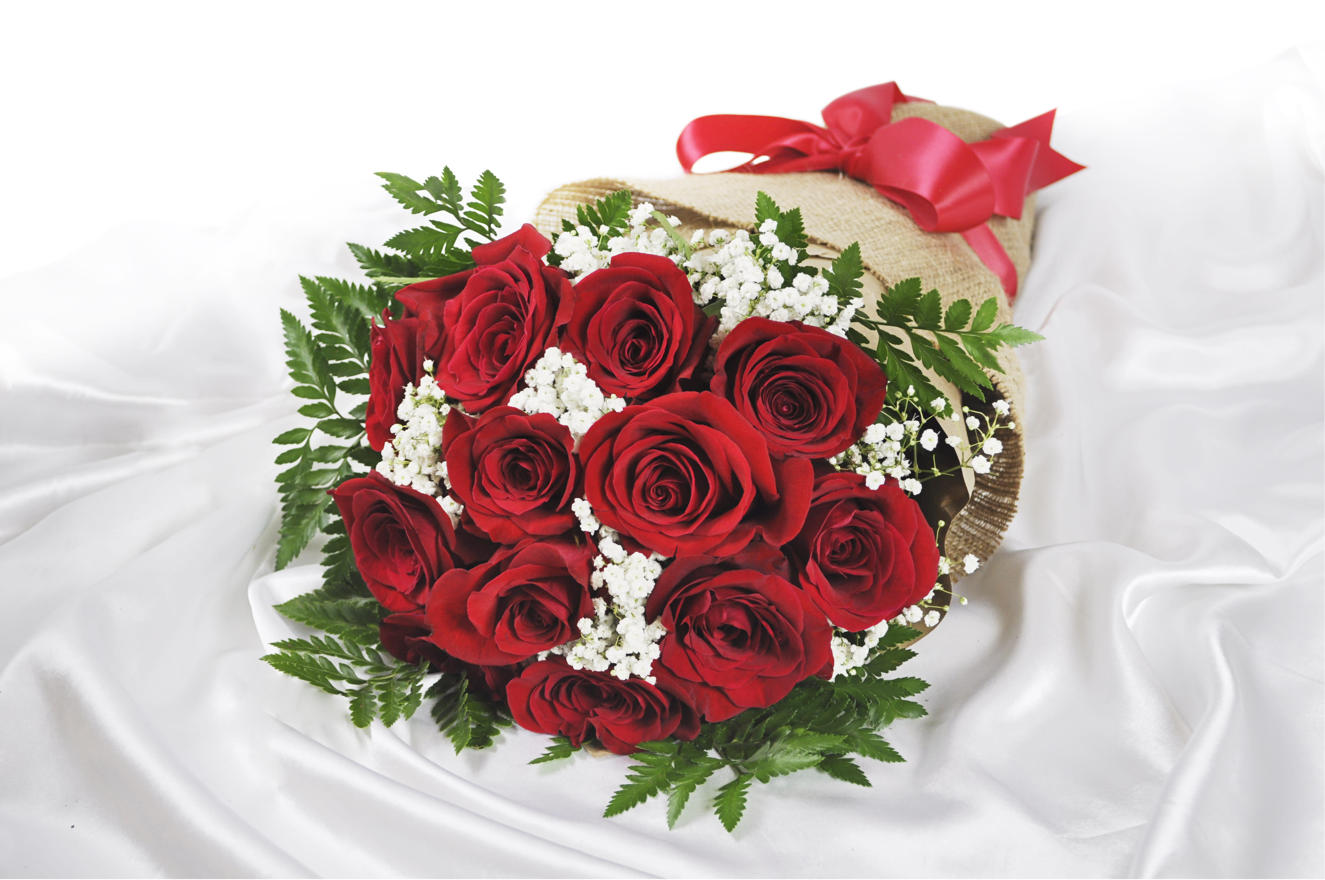 Bouquet of red roses with white baby's breath wrapped in burlap and tied with a red ribbon