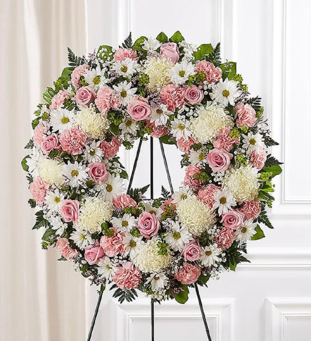 Pink and white floral wreath on a black stand