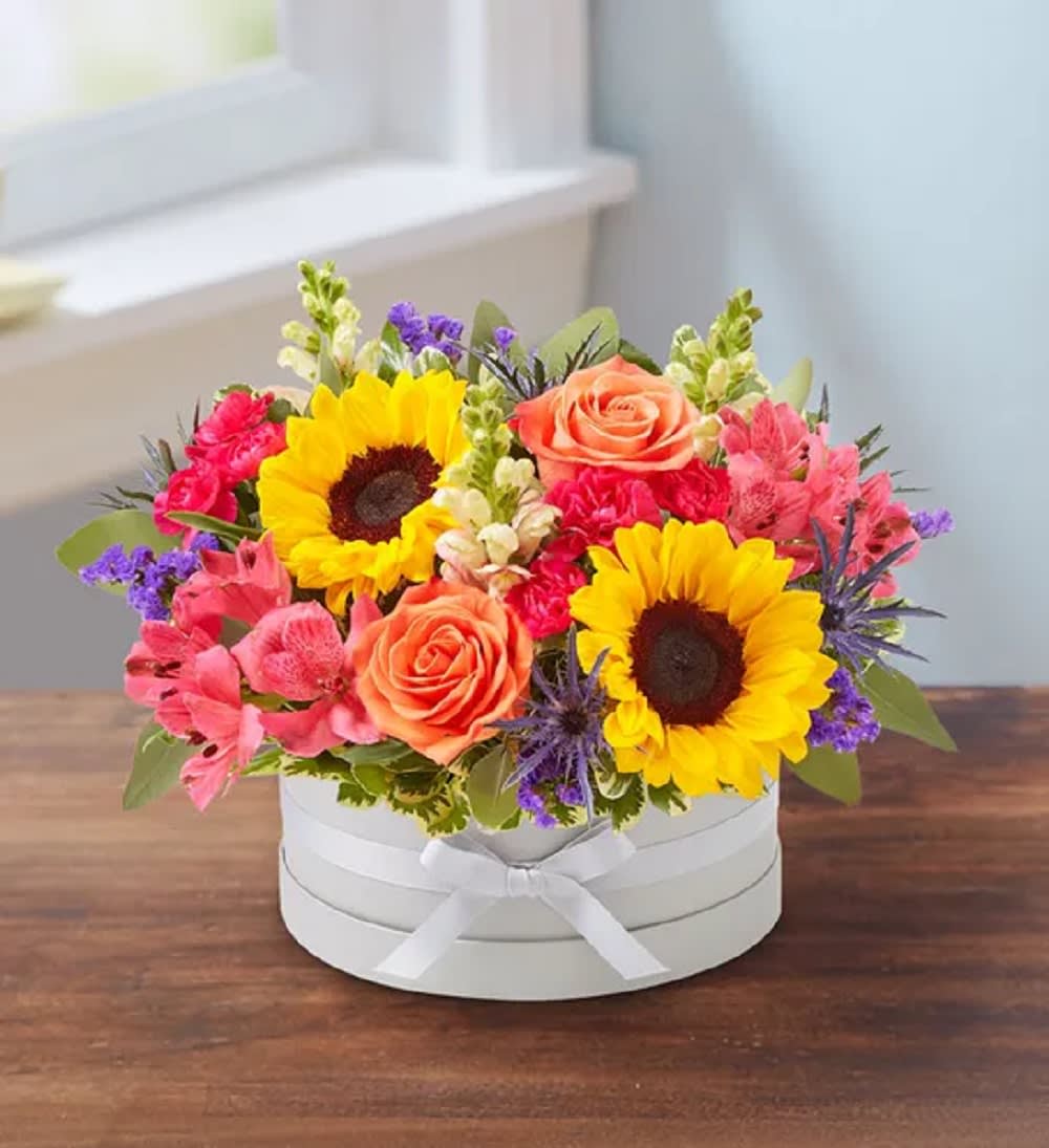 Bright mixed flower arrangement in a white round box with ribbon