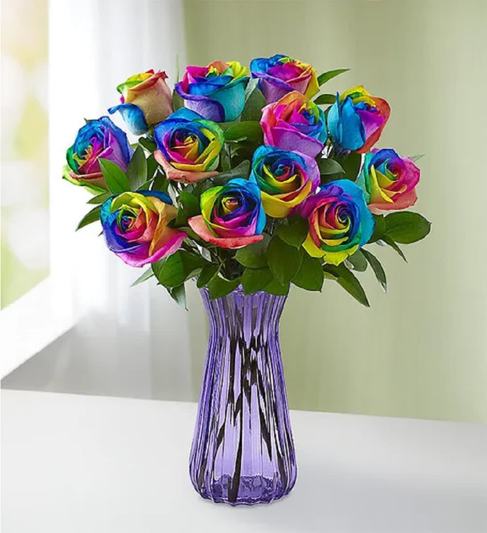 Bouquet of rainbow-colored roses in a purple glass vase