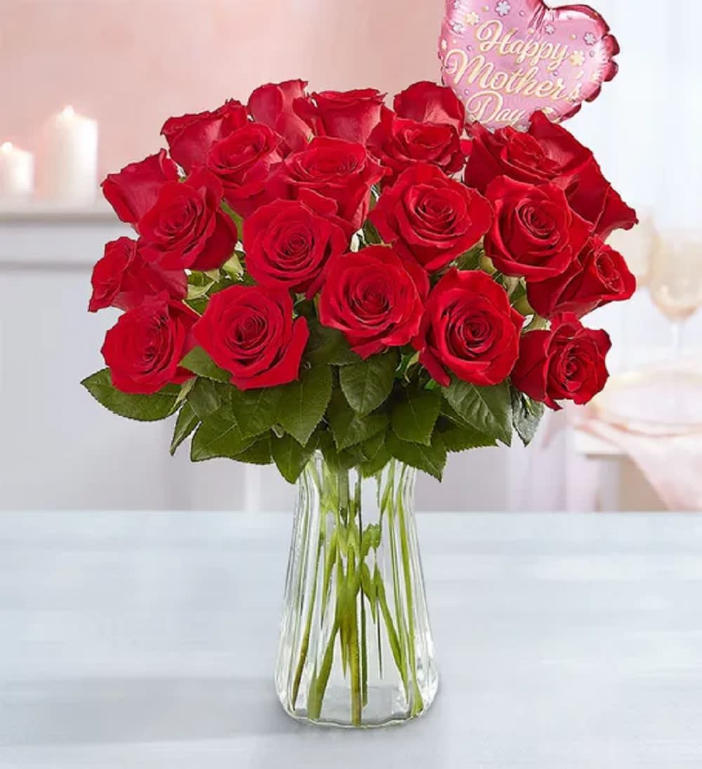 Red roses in a clear glass vase with a pink heart balloon