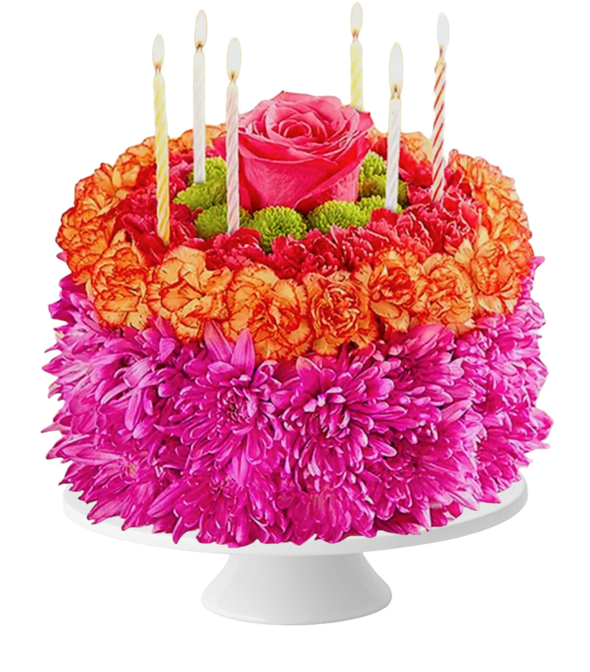 Flower cake with pink roses, orange carnations, and striped candles on a white stand