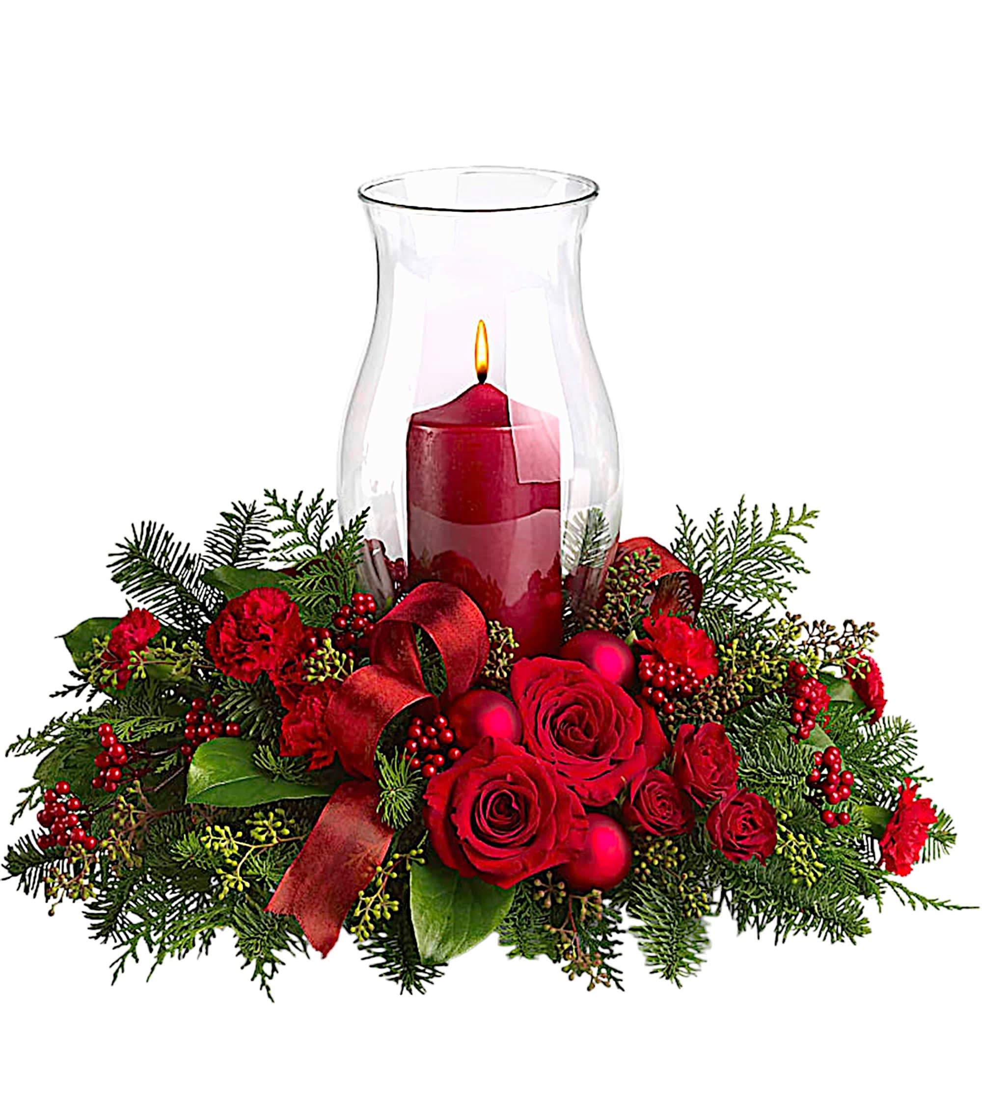 Red roses and carnations around a lit candle in a glass hurricane vase