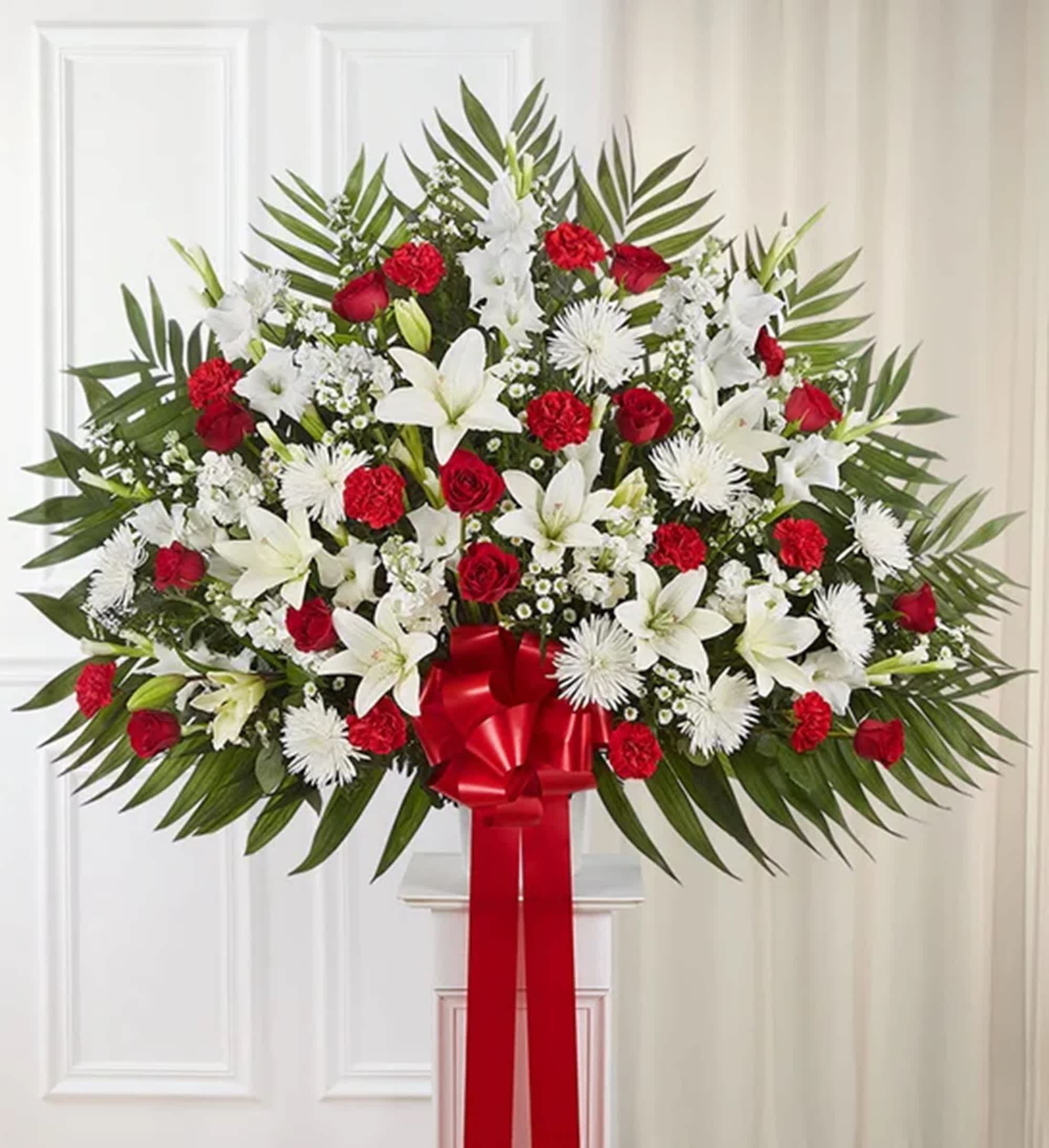 Large standing spray of red and white flowers with a red ribbon