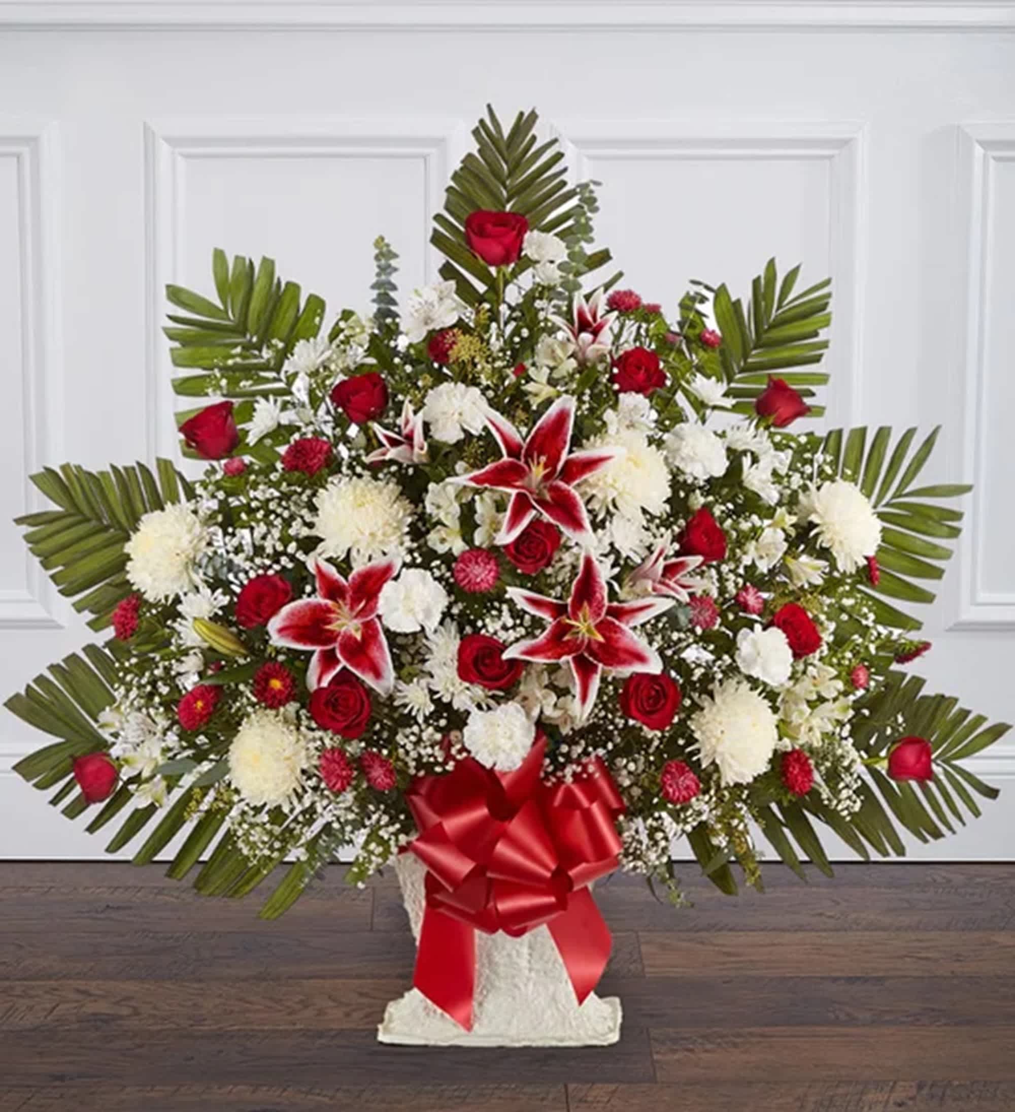 Large red and white floral spray with palm fronds and a red ribbon