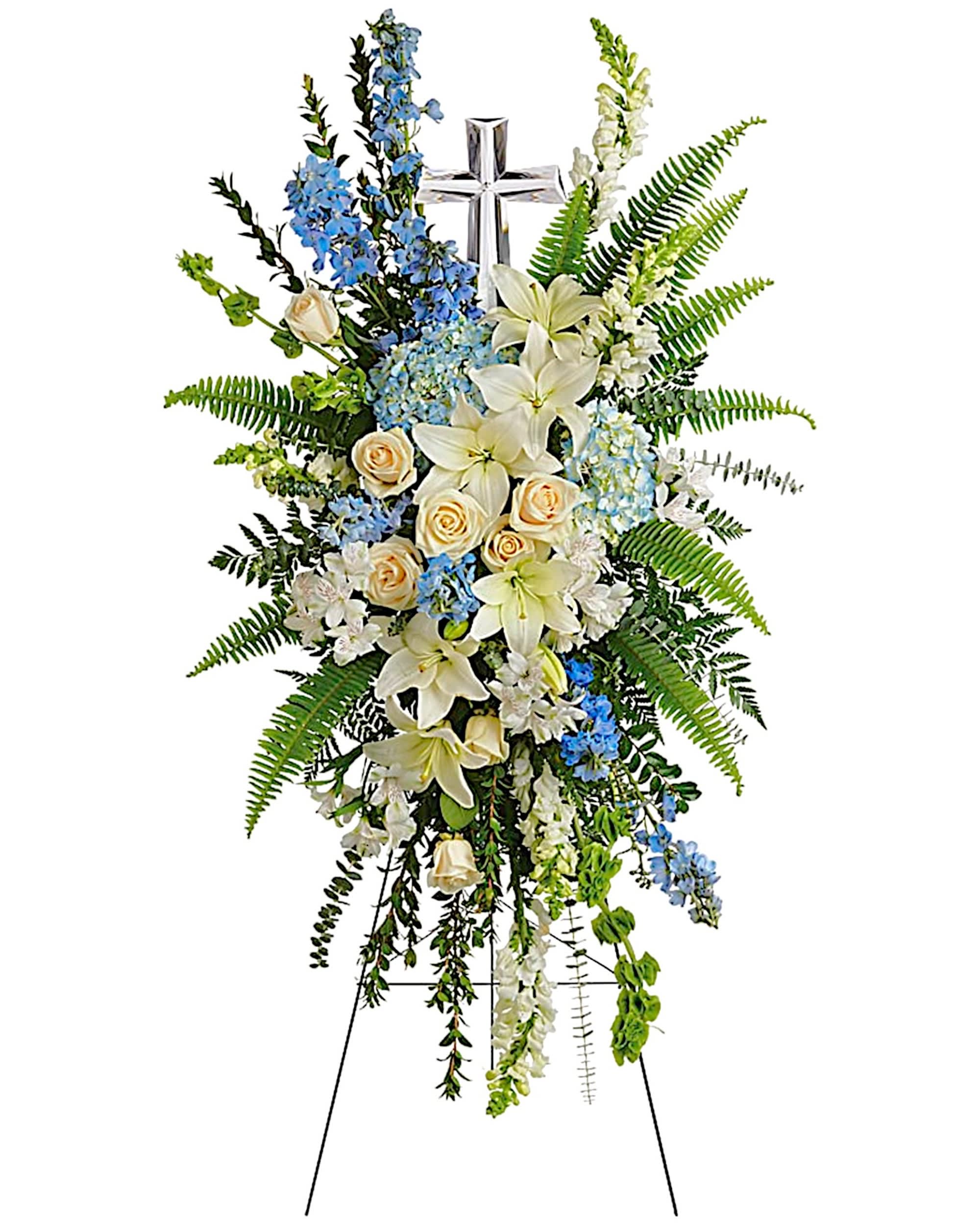 Standing floral spray with white lilies, cream roses, and blue flowers on an easel
