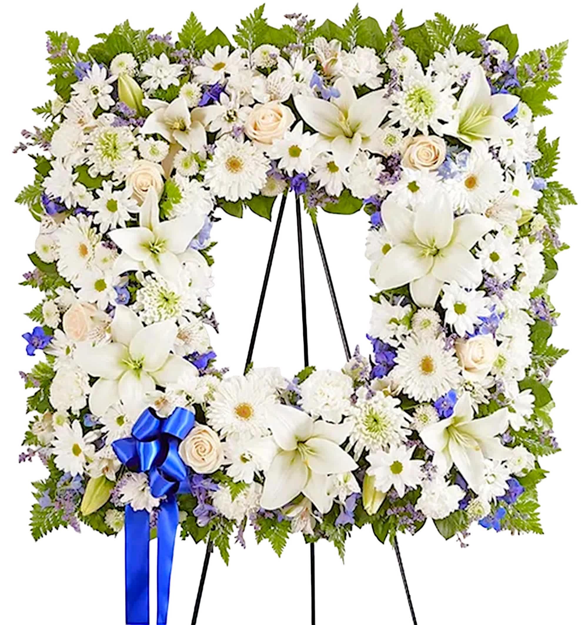 White floral standing wreath on an easel with a blue ribbon