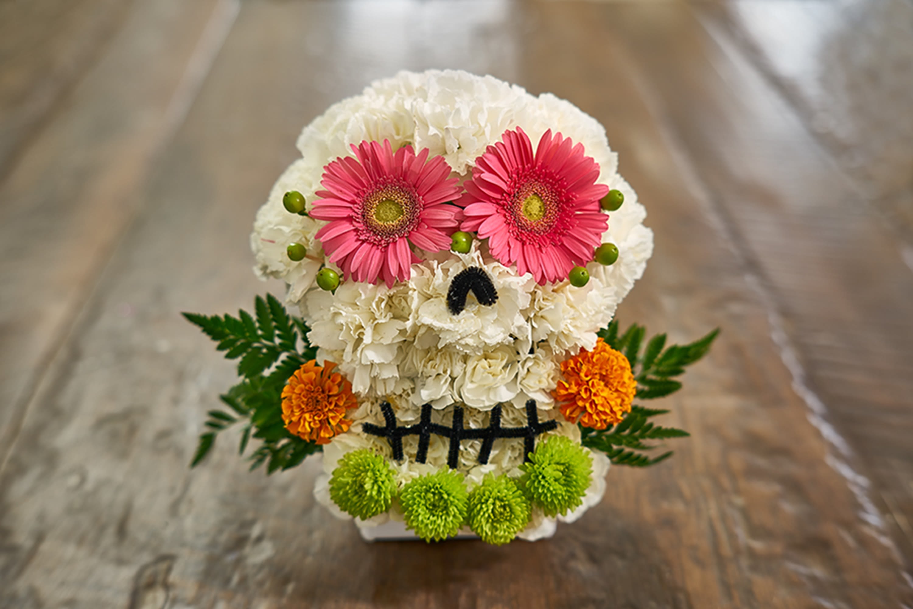 Skull-shaped floral arrangement with pink daisies and white blooms