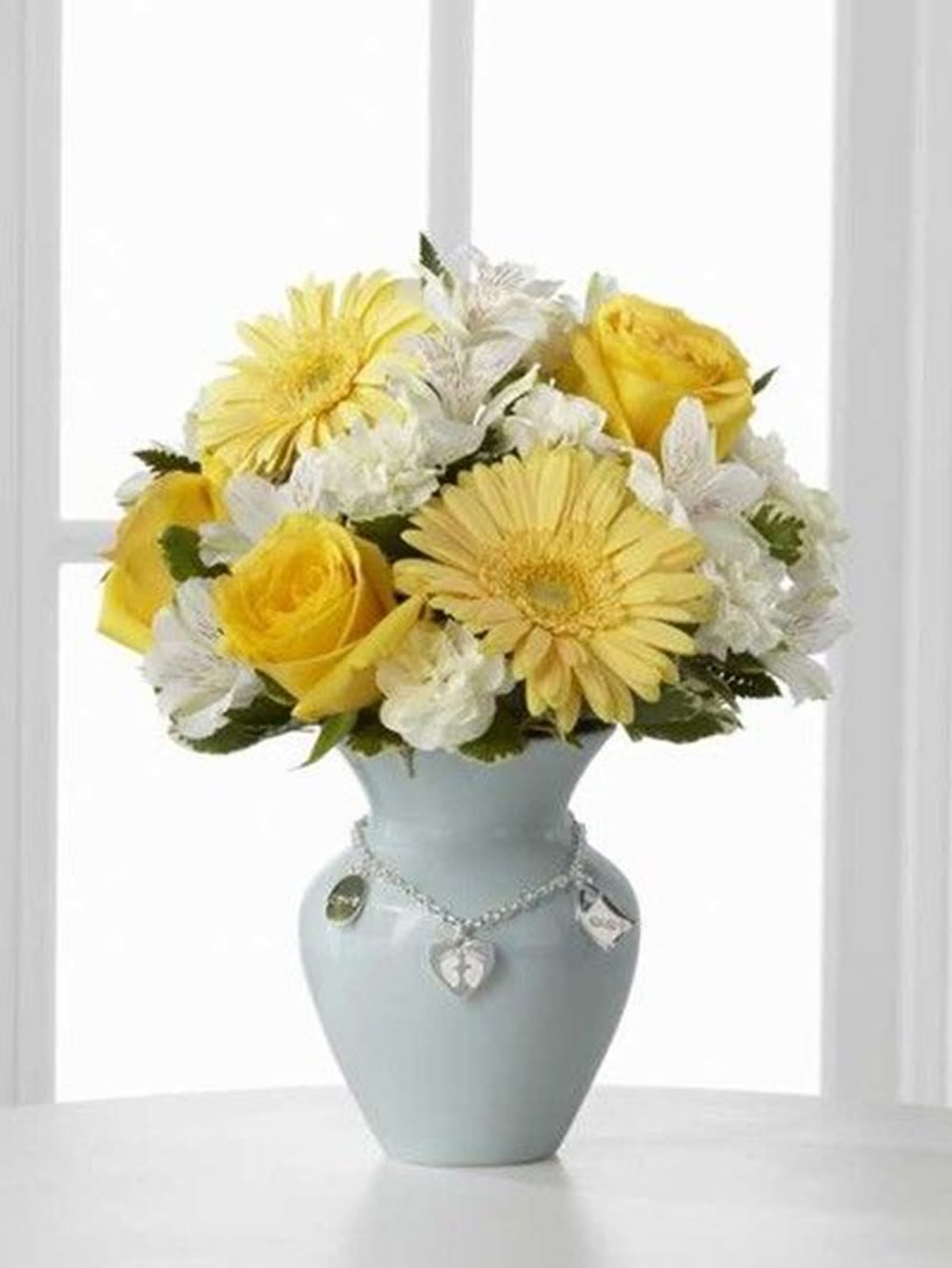 Yellow and white flowers arranged in a pale blue vase