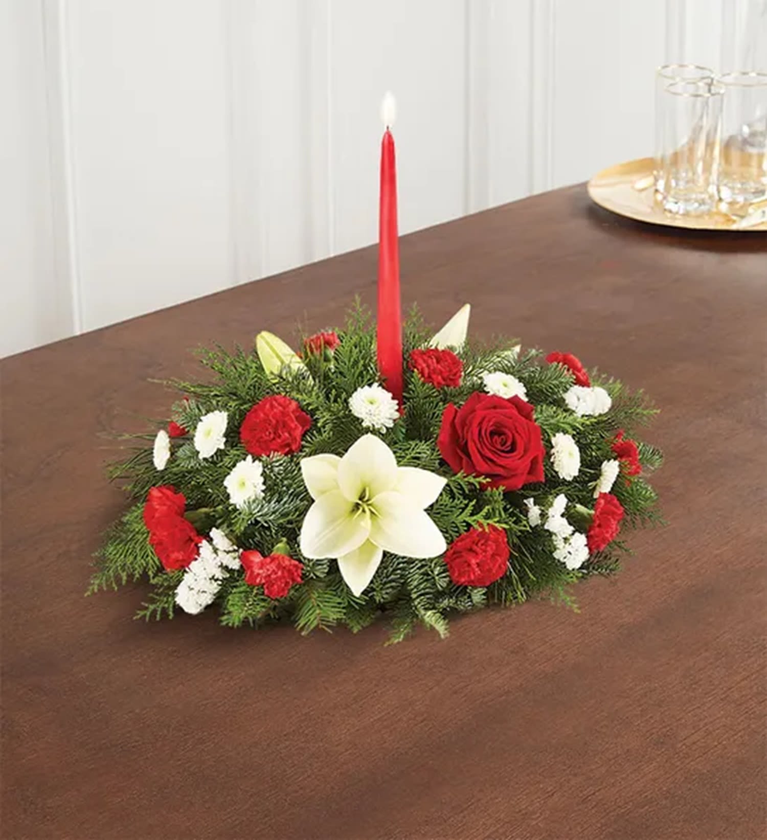 Petite Traditional Christmas Centerpiece - Our traditional table arrangement creates the perfect centerpiece for your Christmas celebration. Beautifully designed with long-lasting blooms in seasonal colors, this fragrant gathering features one red taper candle to cast a warm, cozy glow throughout the holidays.  DETAILS Centerpiece arrangement with red roses, carnations and mini carnations; white Asiatic lilies, button poms and statice; accented with assorted Christmas greenery.   CANDLE INCLUDED (NEVER LEAVE BURNING CANDLE UNATTENDED) Orientation: All-Around Item #NF-779  FLORIST-TO-DOOR Same day flower delivery on most orders placed online by 12 pm or 10 am on weekends PST.  BLOOM DETAILS Roses Asiatic Lilies Button-Mums Mini-Carnations Statice Filler Greenery  Dimensions do not include height of candle. (12") The Standard Arrangement is approx. 7" H x 13" L.  The Deluxe Arrangement is approx. 7.5" H x 14" L. The Premium Arrangement is approx. 7.5" H x 14" L.  How to place an order? 1. You can place an order directly on this secure website OR 2. You can call in your order by dialing: (323) 262 - 9238 OR 3. You can visit our store (appointment recommended 323.262.9238)  NINFA'S FLOWERS 2405 WHITTIER BLVD. LOS ANGELES, CA. 90023