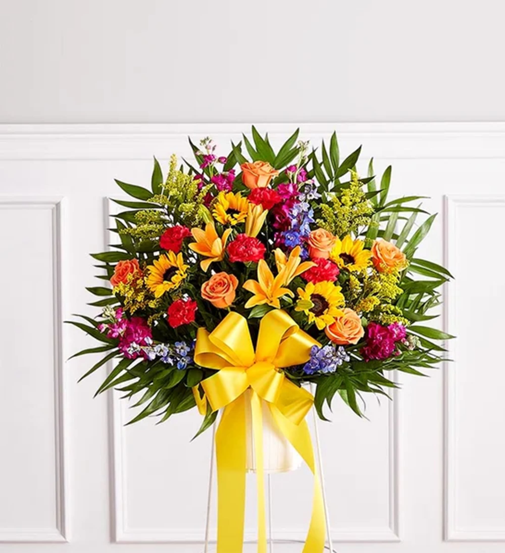 Heartfelt Sympathies Standing Basket - Their joy and exuberance will always be remembered. The classic standing basket arrangement was designed to capture that lively spirit. Elegantly crafted for a lush, full presentation, this vibrant mix of blooms creates a memorable tribute to someone who was truly one-of-a-kind. Appropriate for the funeral services, memorial service, or graveside.  DETAILS One-sided standing basket arrangement with orange roses and Asiatic lilies, yellow sunflowers and solidago, blue delphinium, fuchsia stock, and hot pink carnations; accented with assorted greenery and yellow ribbon  BASKET CONTAINER INCLUDED Orientation: One-Sided Item #NF-1313  FLORIST-TO-DOOR Same day flower delivery on most orders placed online by 12 pm or 10 am on weekends PST.  BLOOM DETAILS Roses Asiatic Lilies Sunflowers Delphinium Stock Carnations Solidago Greenery  The Standard Arrangement is approx. 32"H x 32"W  The Deluxe Arrangement is approx. 34"H x 36"W The Premium Arrangement is approx. 36"H x 40"W  How to place an order? 1. You can place an order directly on this secure website OR 2. You can call in your order by dialing: (323) 262 - 9238 OR 3. You can visit our store (appointment recommended 323.262.9238)  NINFA'S FLOWERS 2405 WHITTIER BLVD. LOS ANGELES, CA. 90023