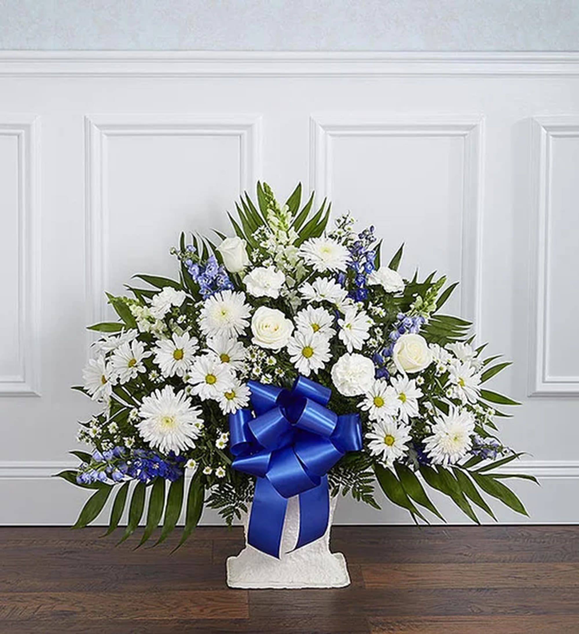 White floral standing spray with a blue ribbon on a pedestal base