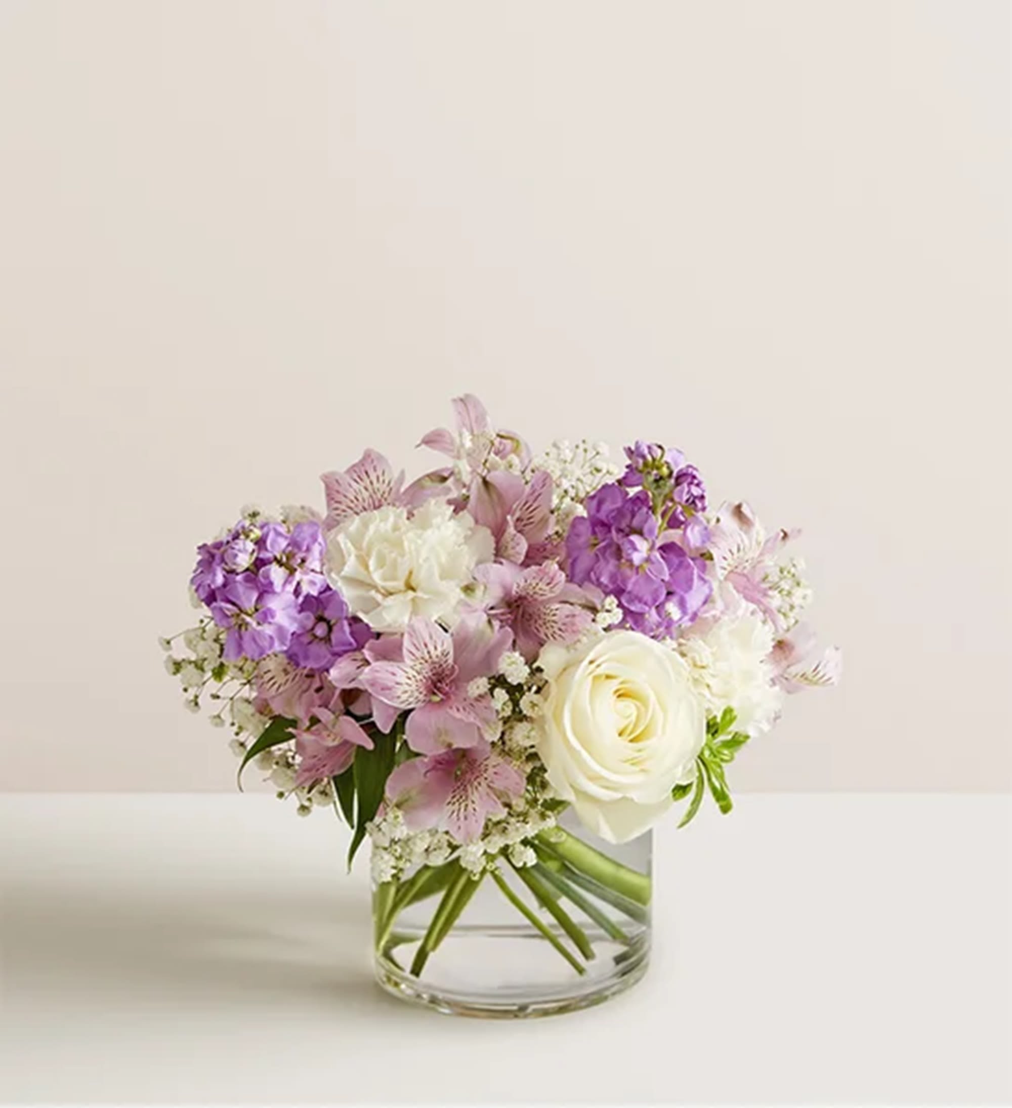 Bouquet of white roses and pink-purple flowers in a clear glass vase