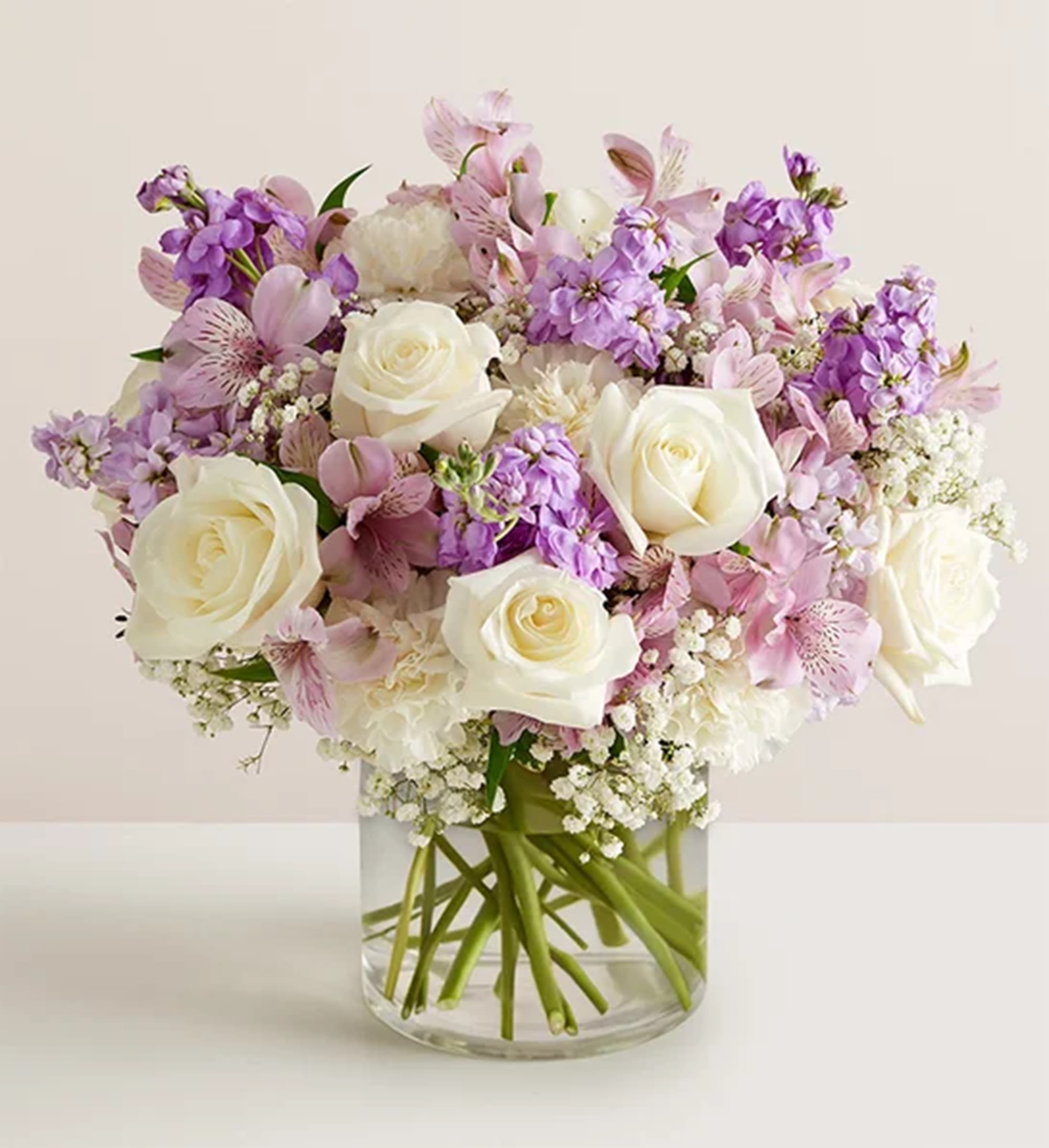 Bouquet of white roses and pink-purple flowers in a clear glass vase