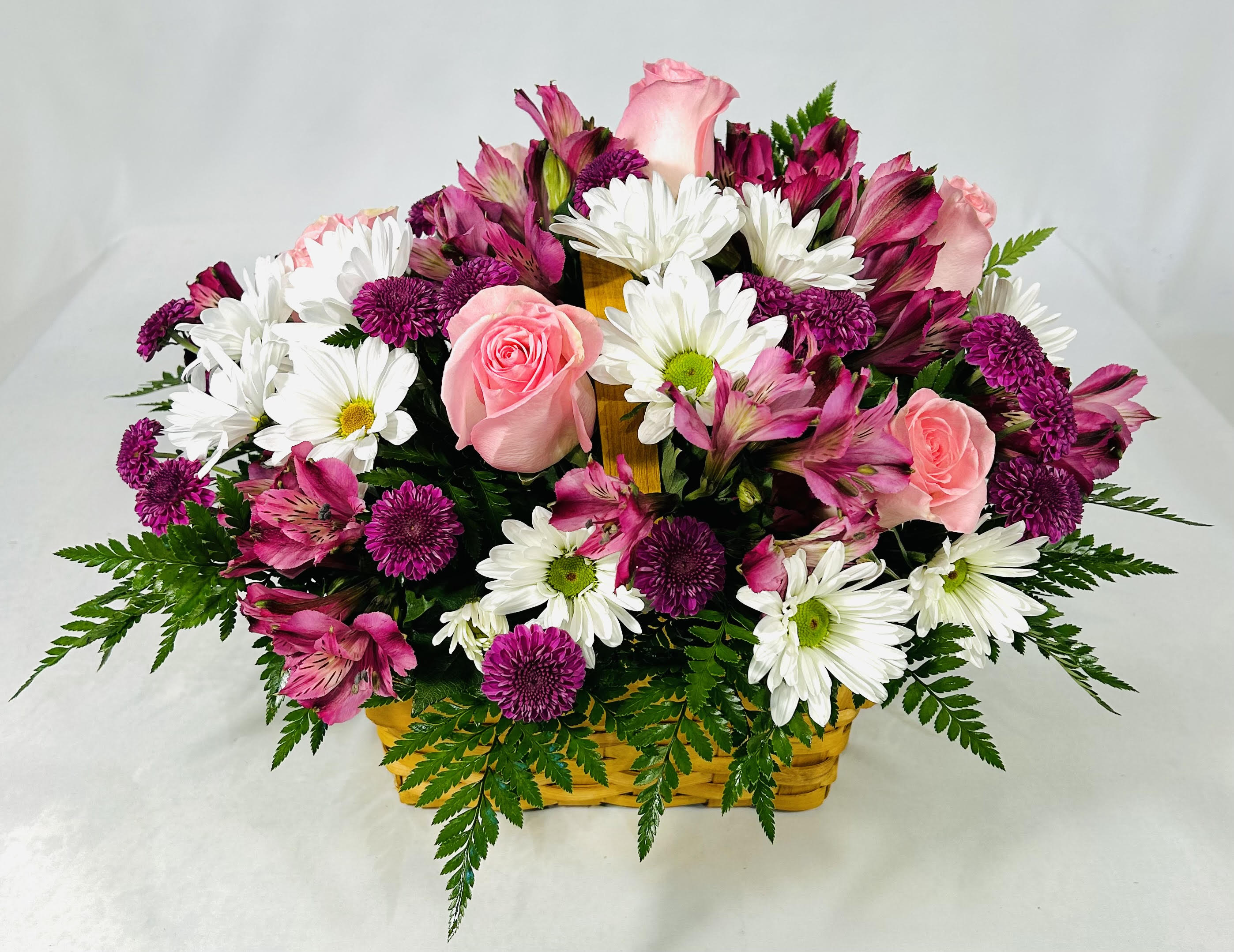 Basket arrangement of pink roses, purple mums, white daisies, and pink alstroemeria