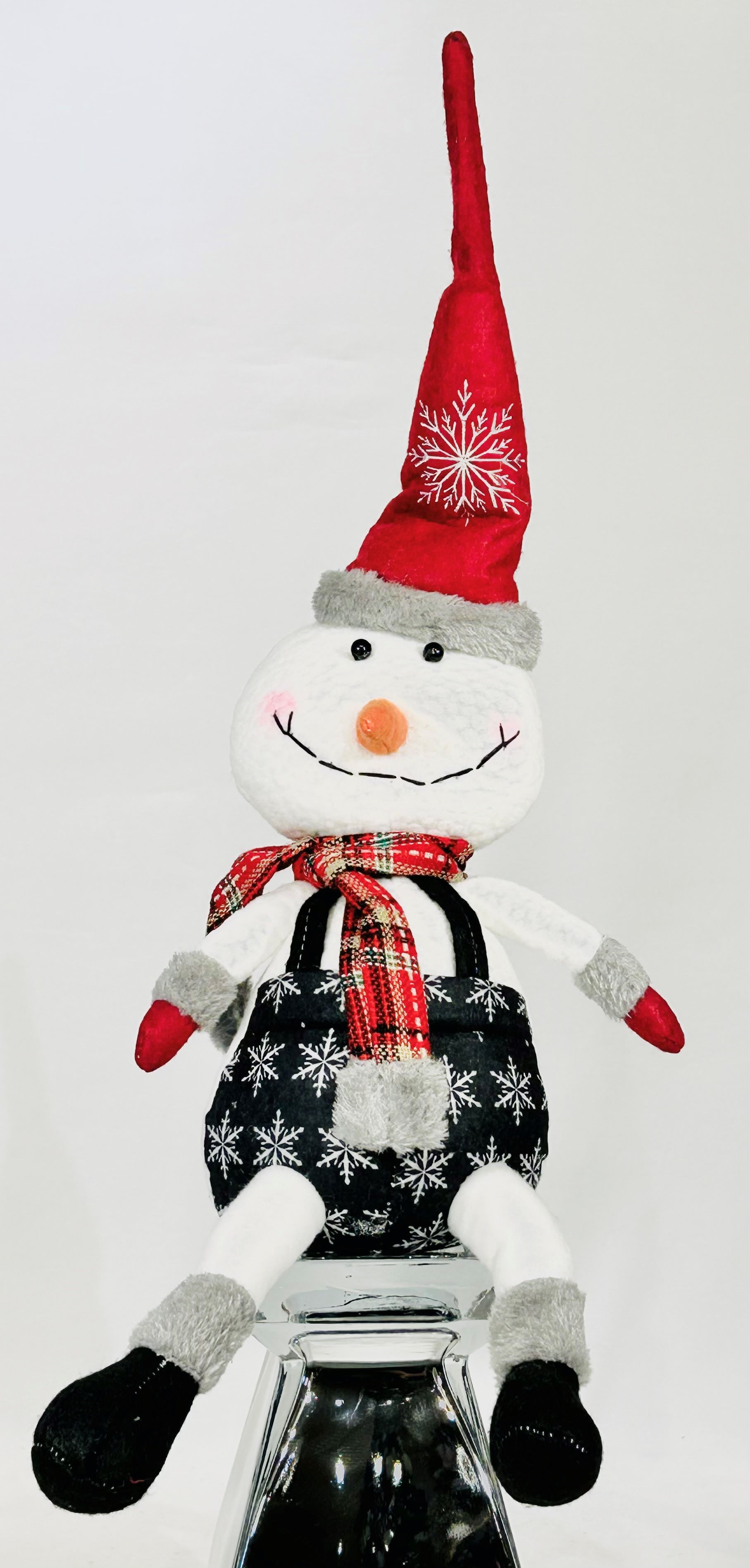 Plush snowman decoration with a red hat and scarf sitting on a glass stand