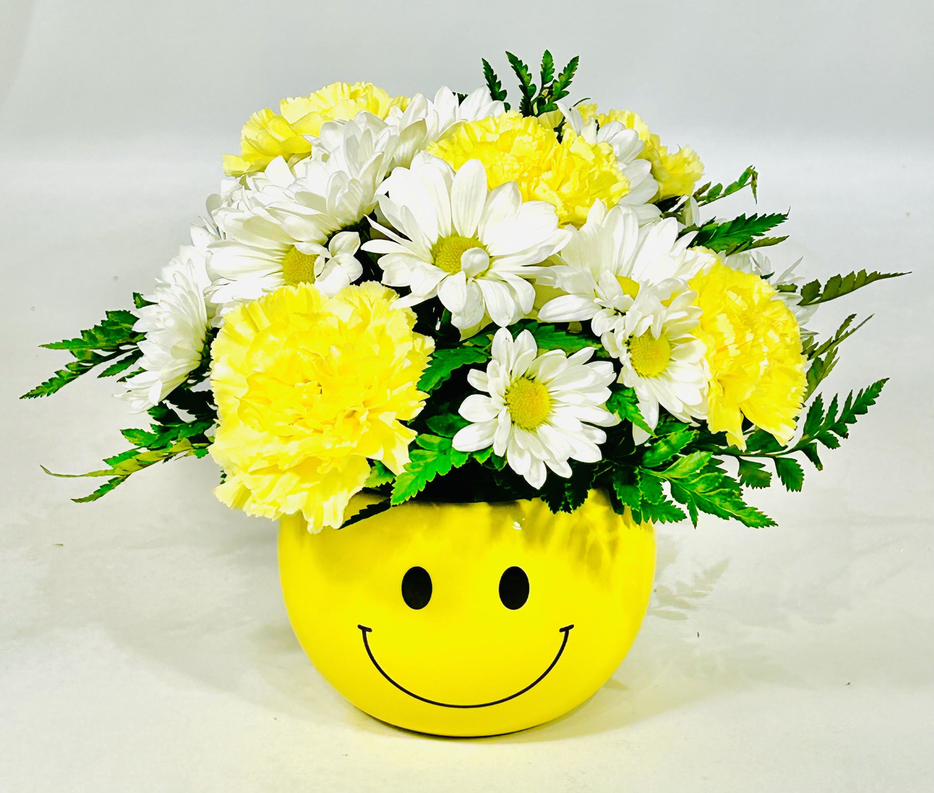 Yellow and white daisy bouquet in a smiley-face pot