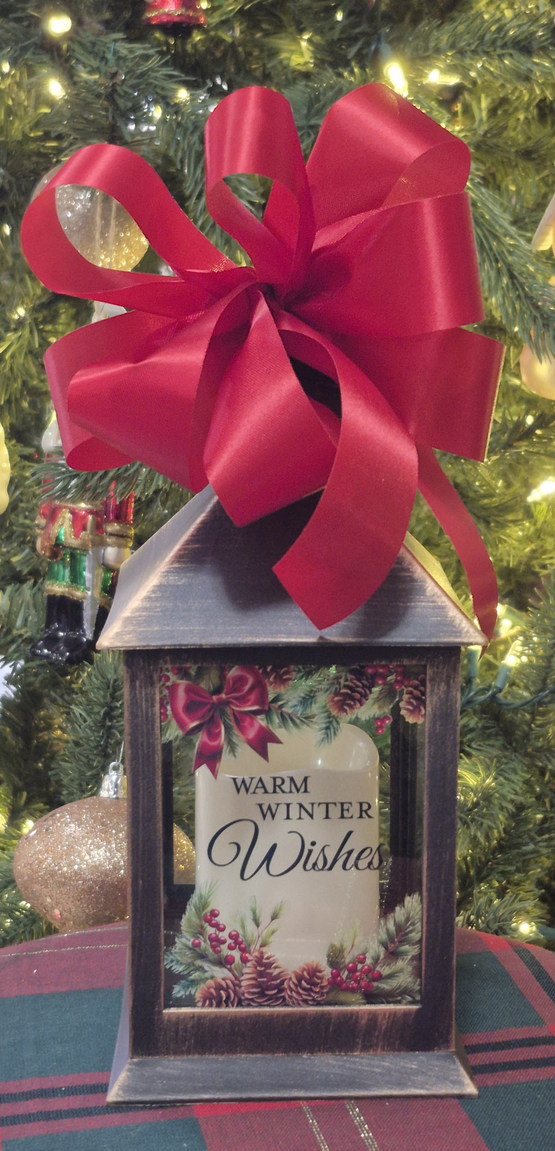 Holiday lantern with a red bow and a "Warm Winter Wishes" candle inside