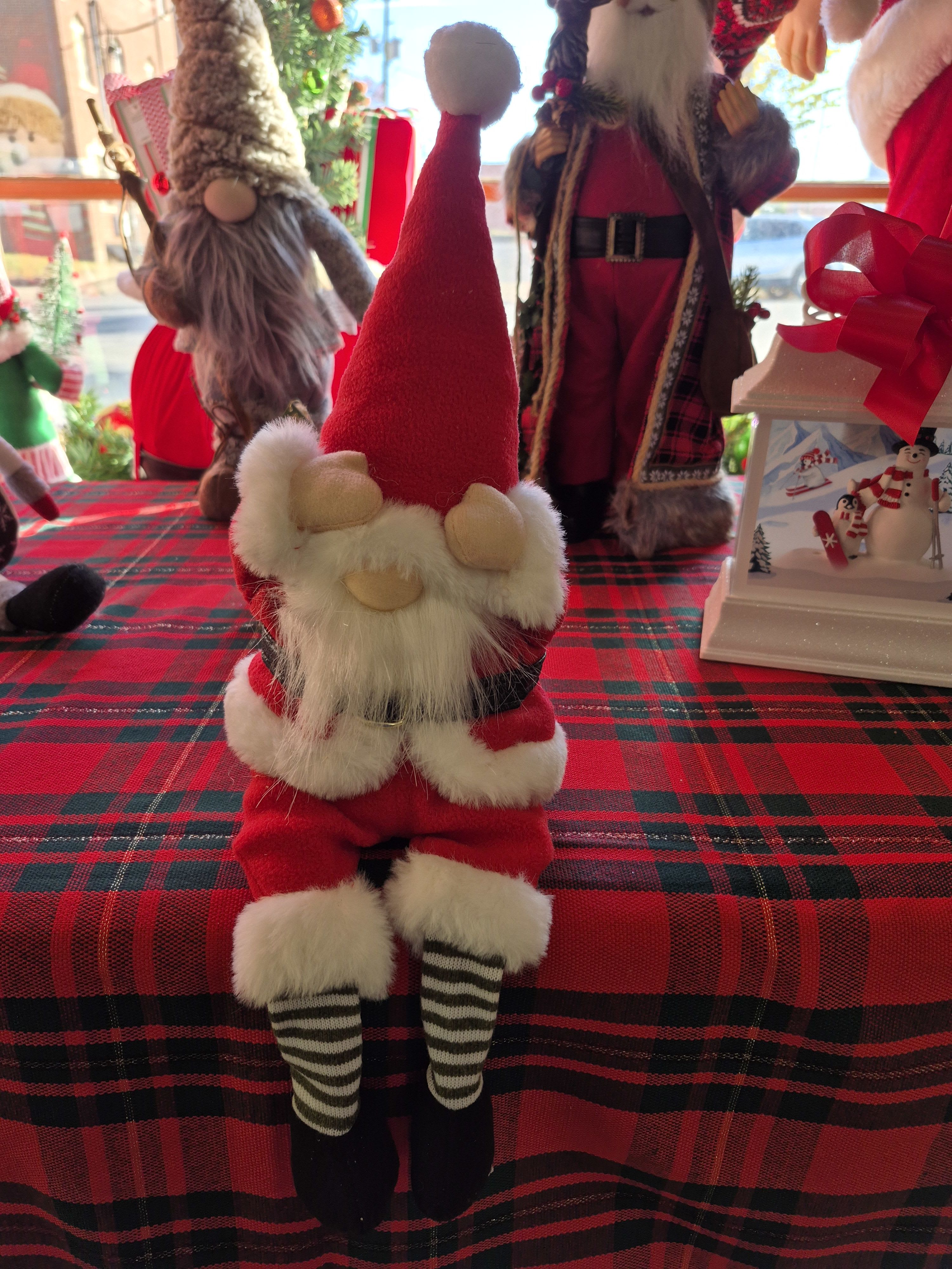 Santa figurine on a red plaid tablecloth with other holiday decorations