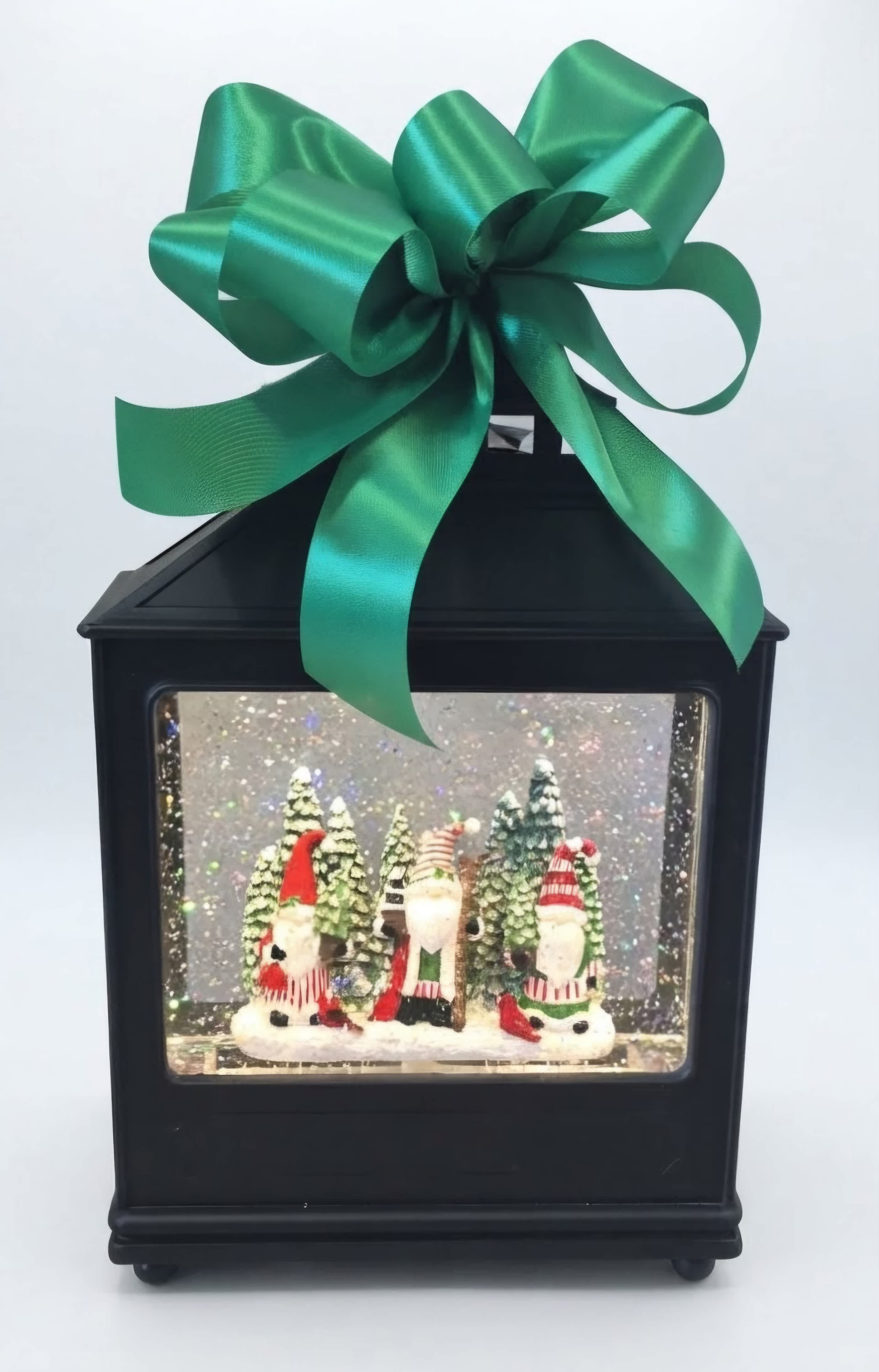 Black lantern with a large green bow and a Christmas gnome scene inside