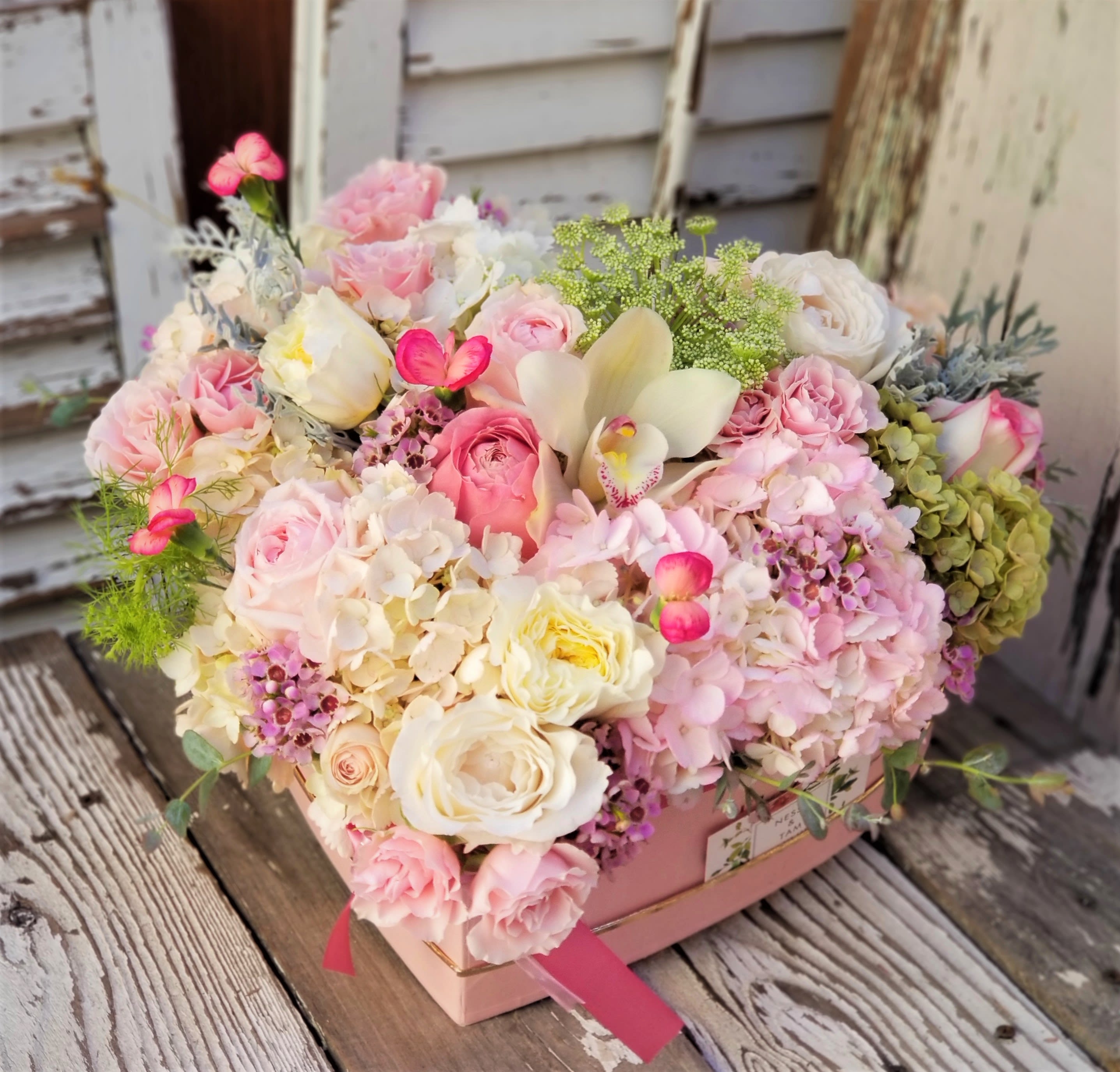 Pink and white mixed flower arrangement in a pink box