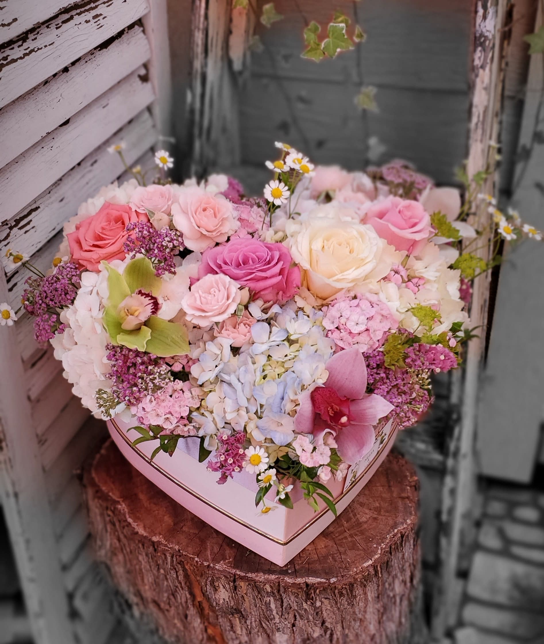 Heart-shaped box filled with pink and white roses and mixed flowers