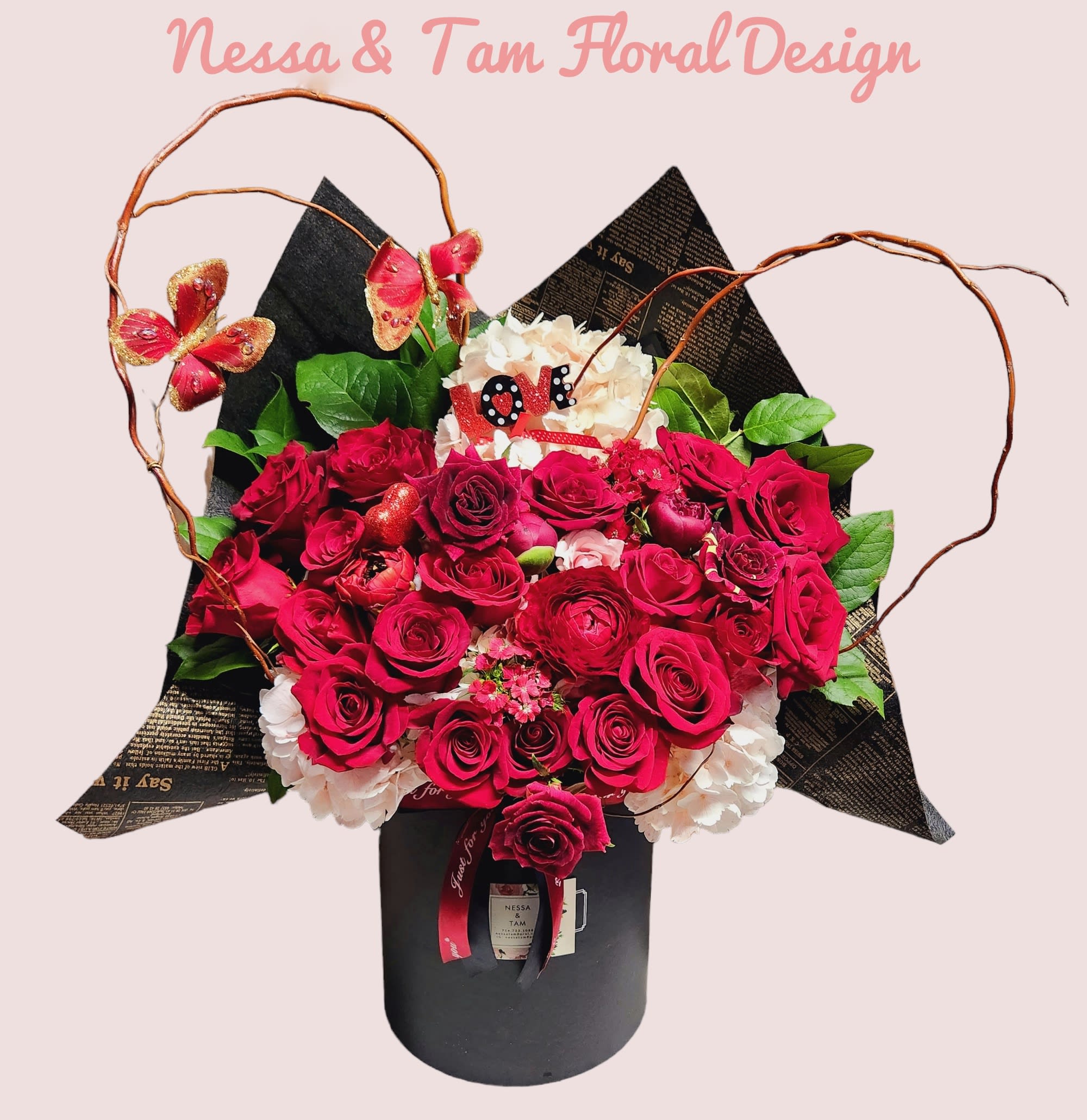 Bouquet of red roses and white hydrangeas in a black box with butterfly accents