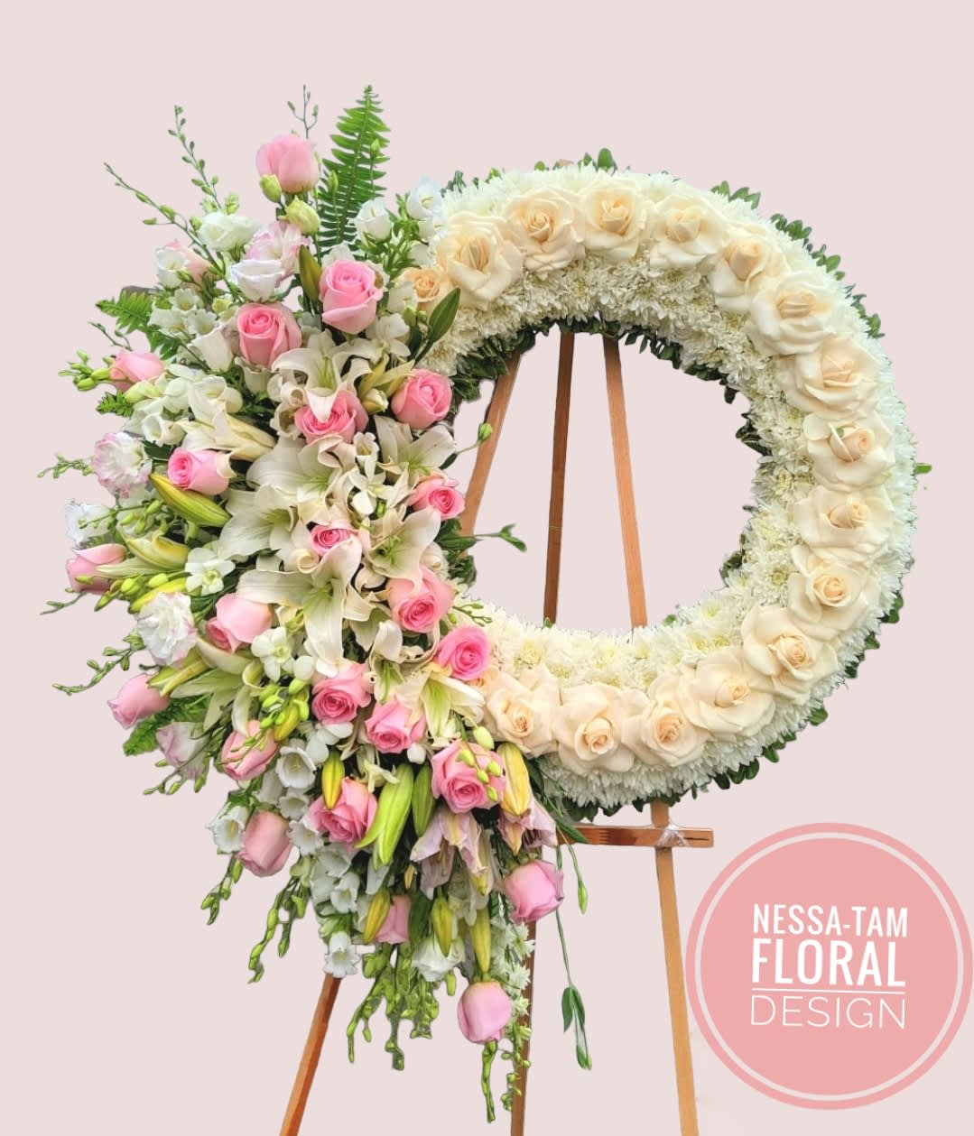 Floral wreath on an easel with pink and cream roses and lilies