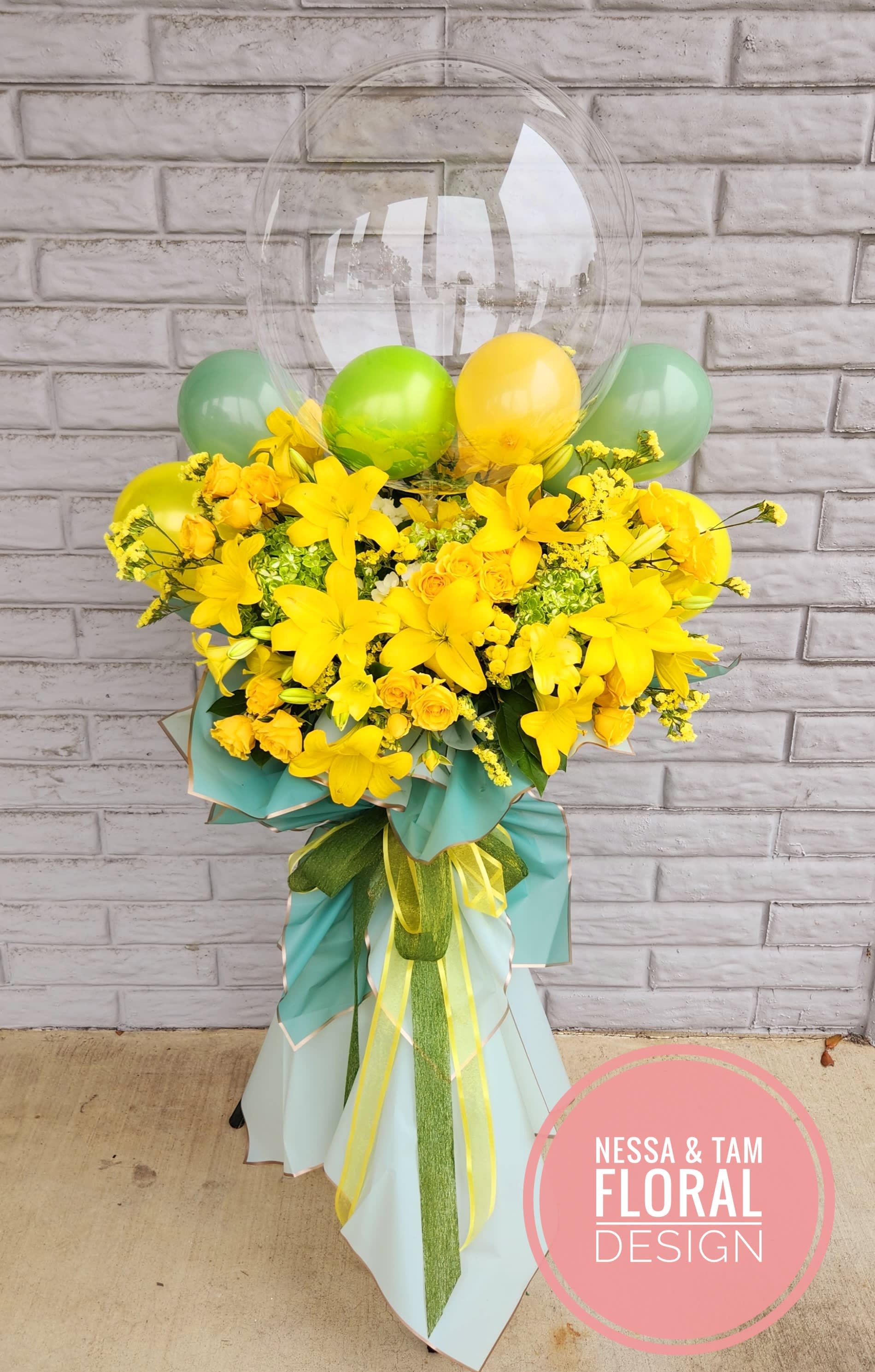 Yellow floral arrangement with balloons and a clear balloon topper