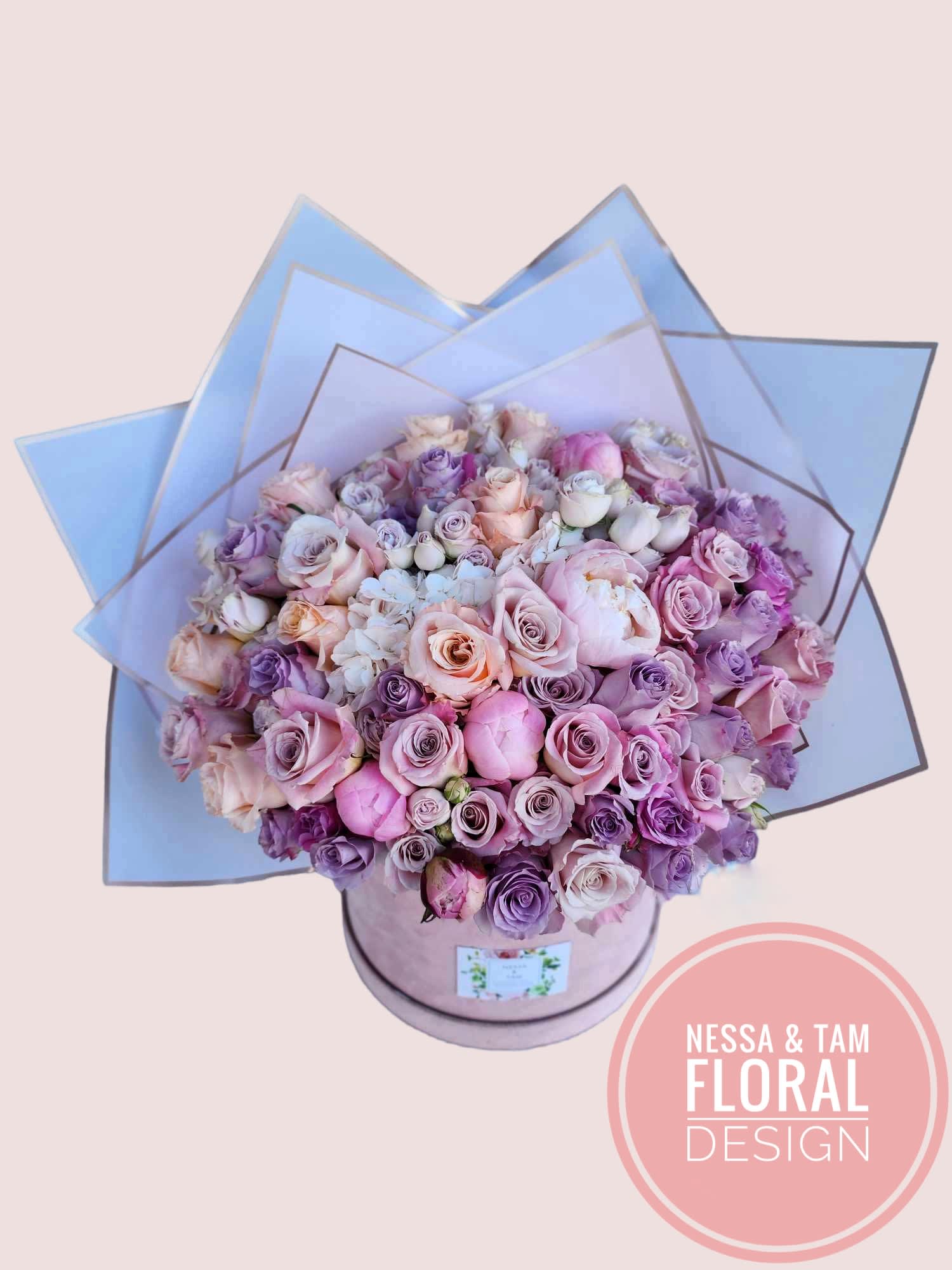 Large bouquet of pink and lavender roses in a round box