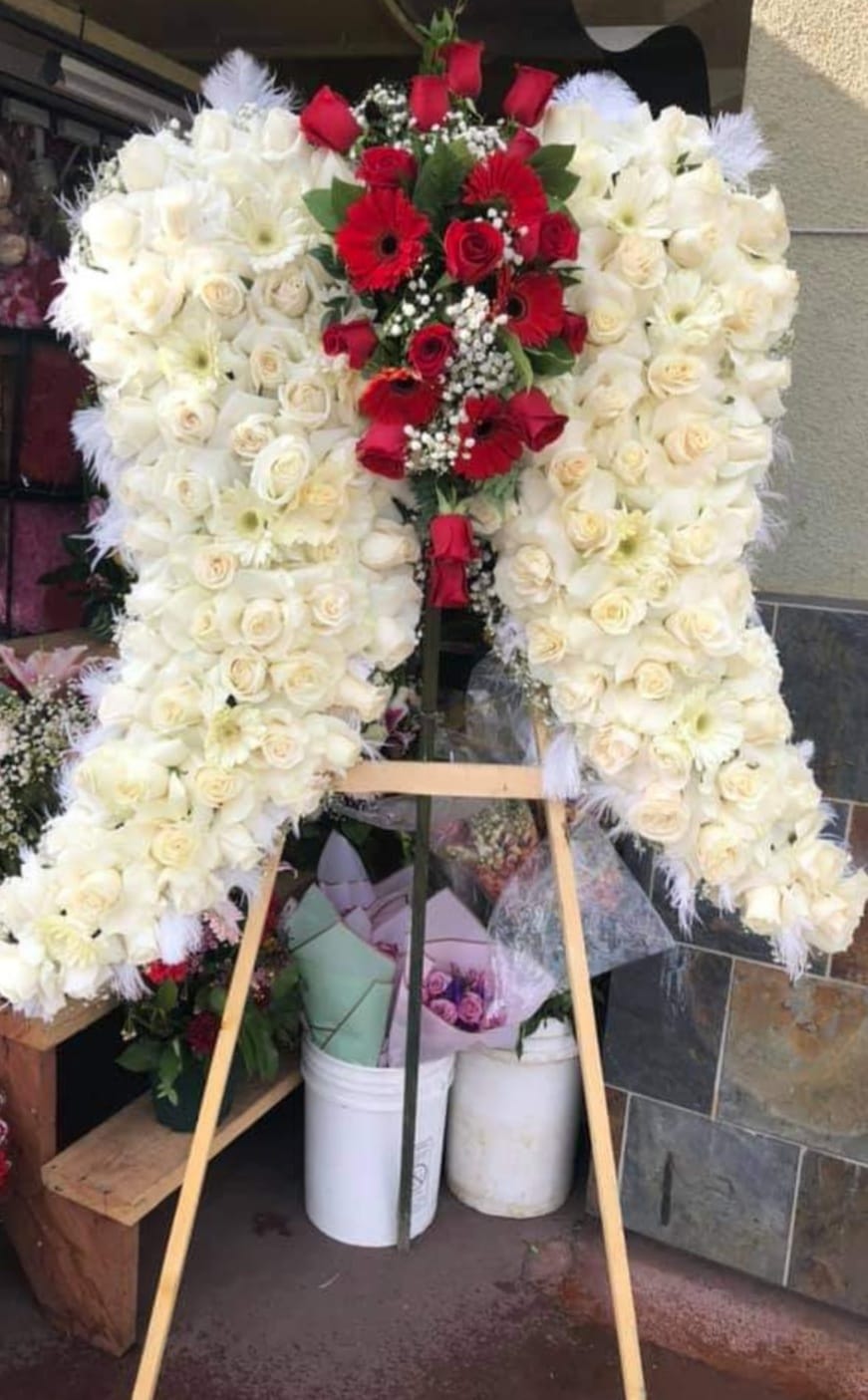 Large standing floral wreath of white and red roses on an easel