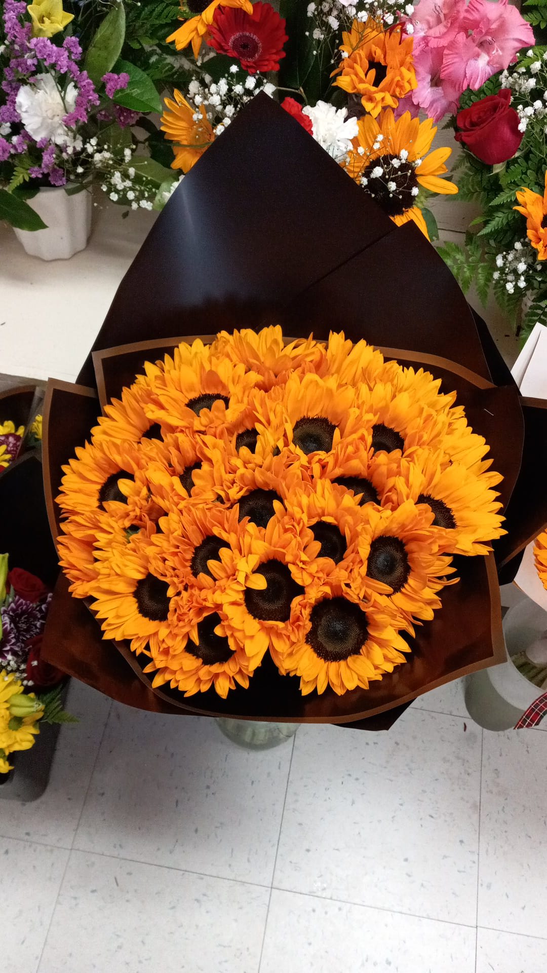 Bouquet of orange sunflowers wrapped in dark paper