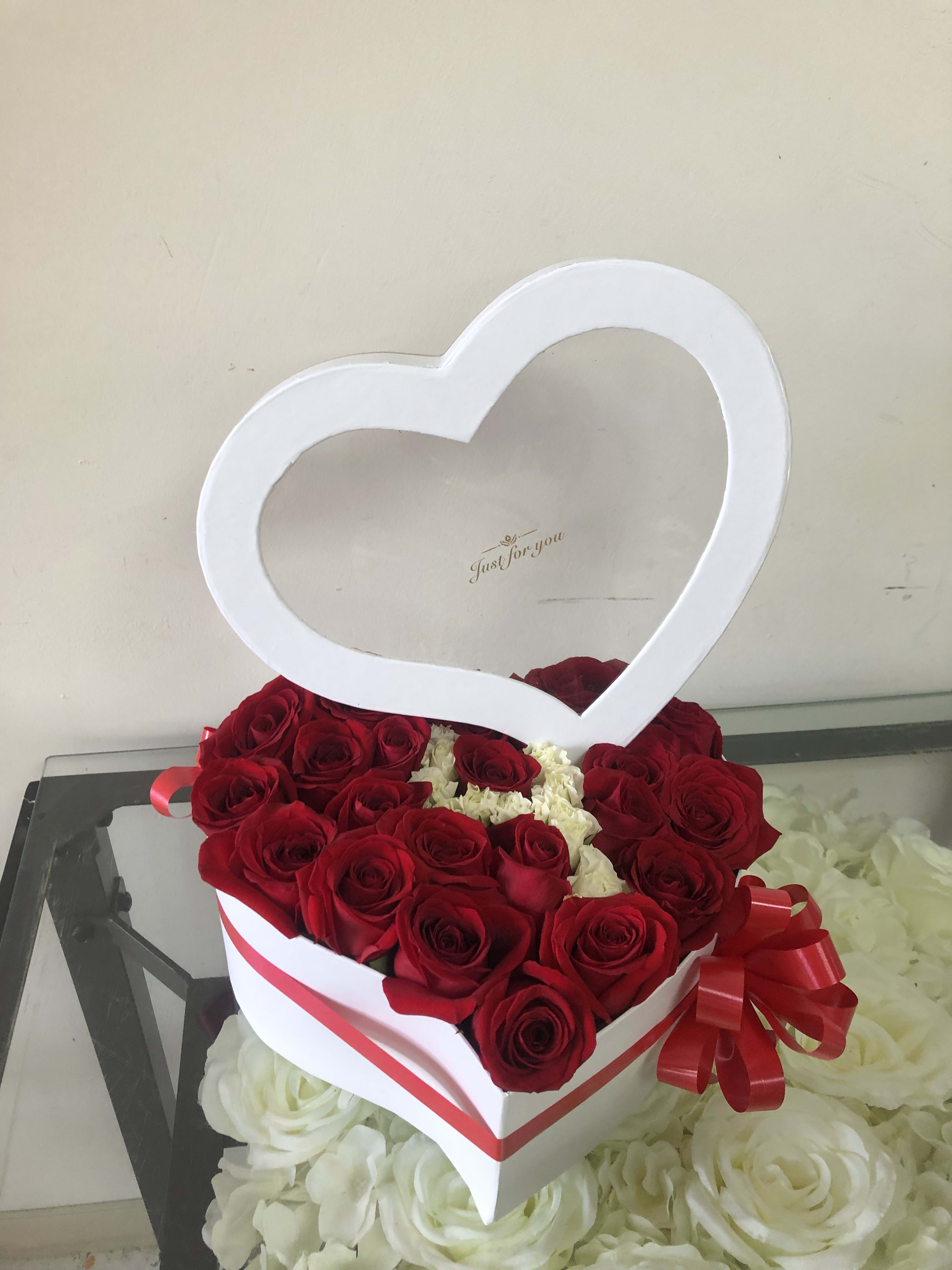 Heart-shaped box of red roses with a white heart topper and red ribbon