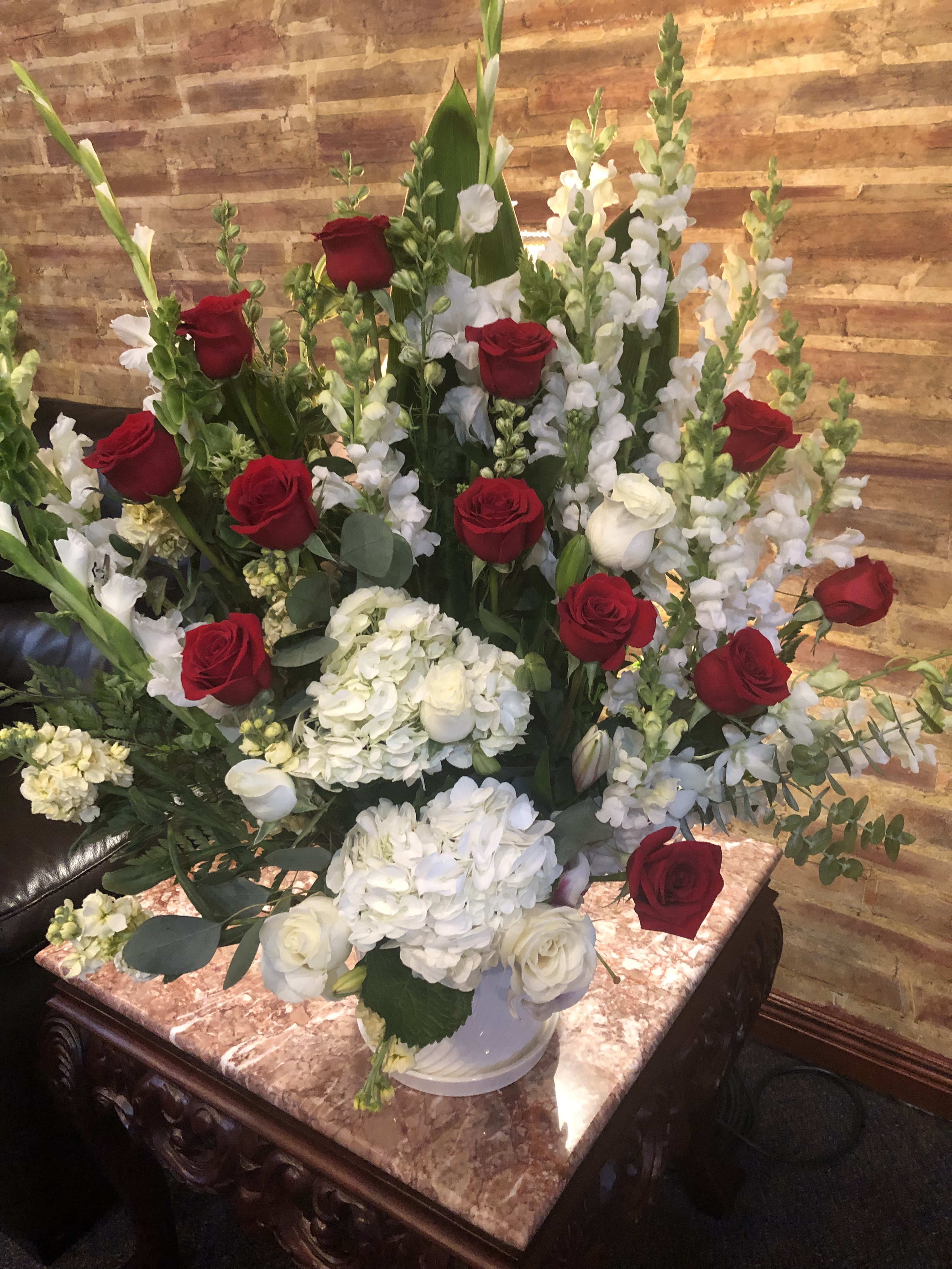 Red roses and white flowers arranged in a large vase
