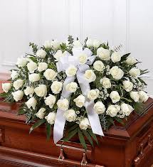 White rose casket spray with ribbon on a wooden casket