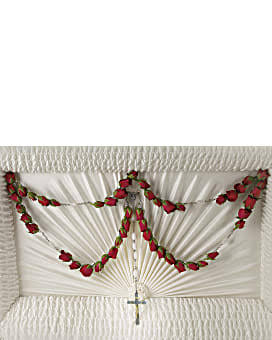 White funeral casket with red rose garland and cross