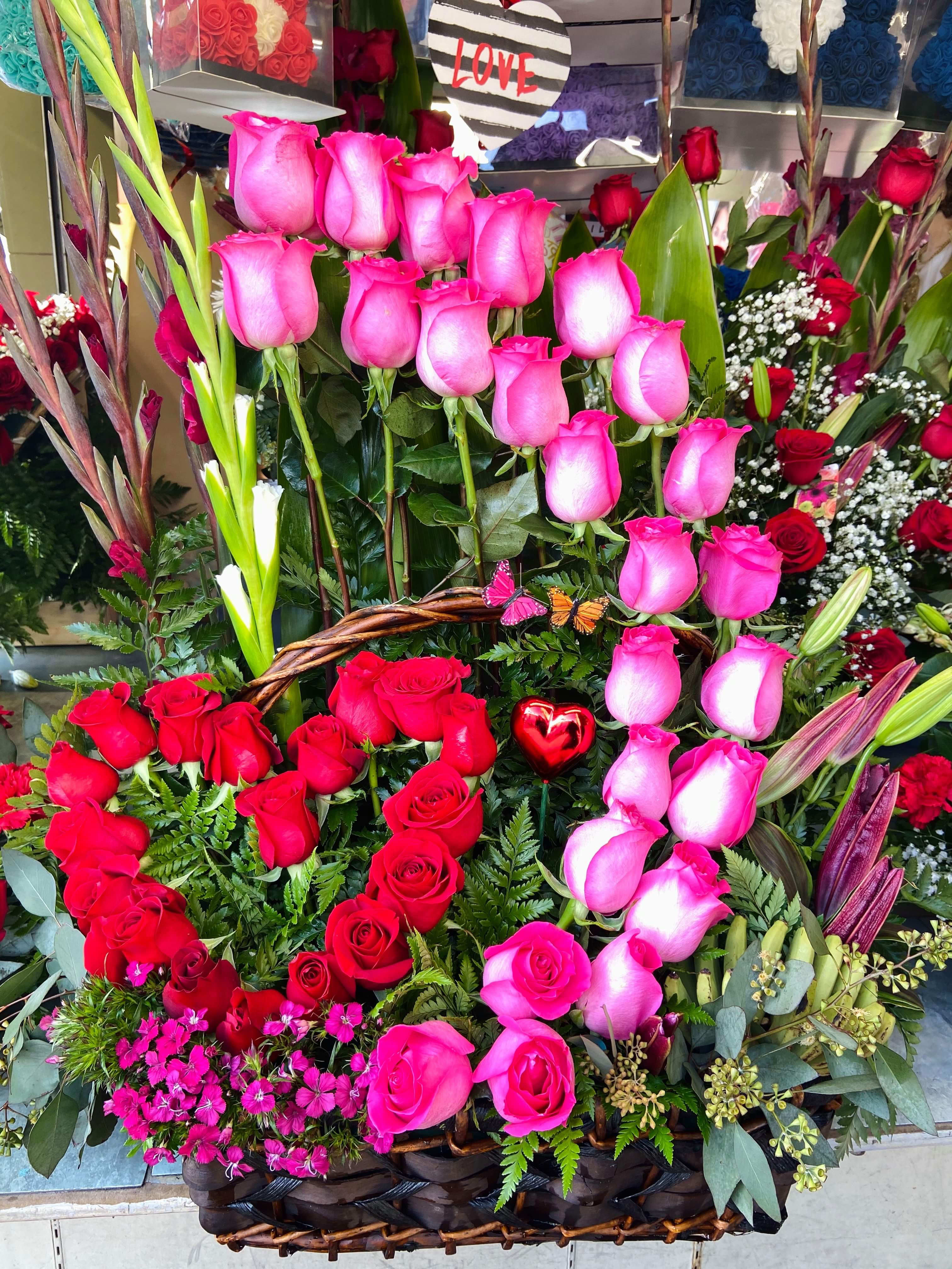 Basket arrangement of pink and red roses with lilies and greenery
