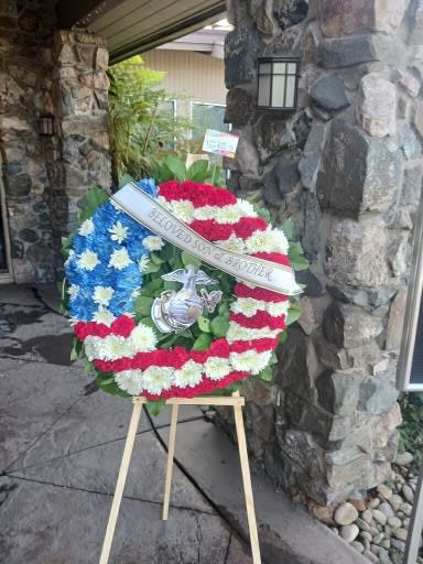 Patriotic floral wreath on an easel with red, white, and blue flowers