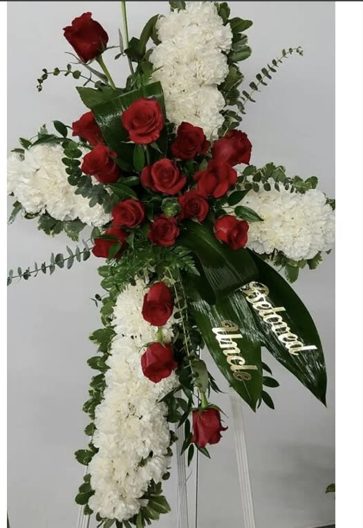 Standing floral spray with red roses and white blooms on a white easel