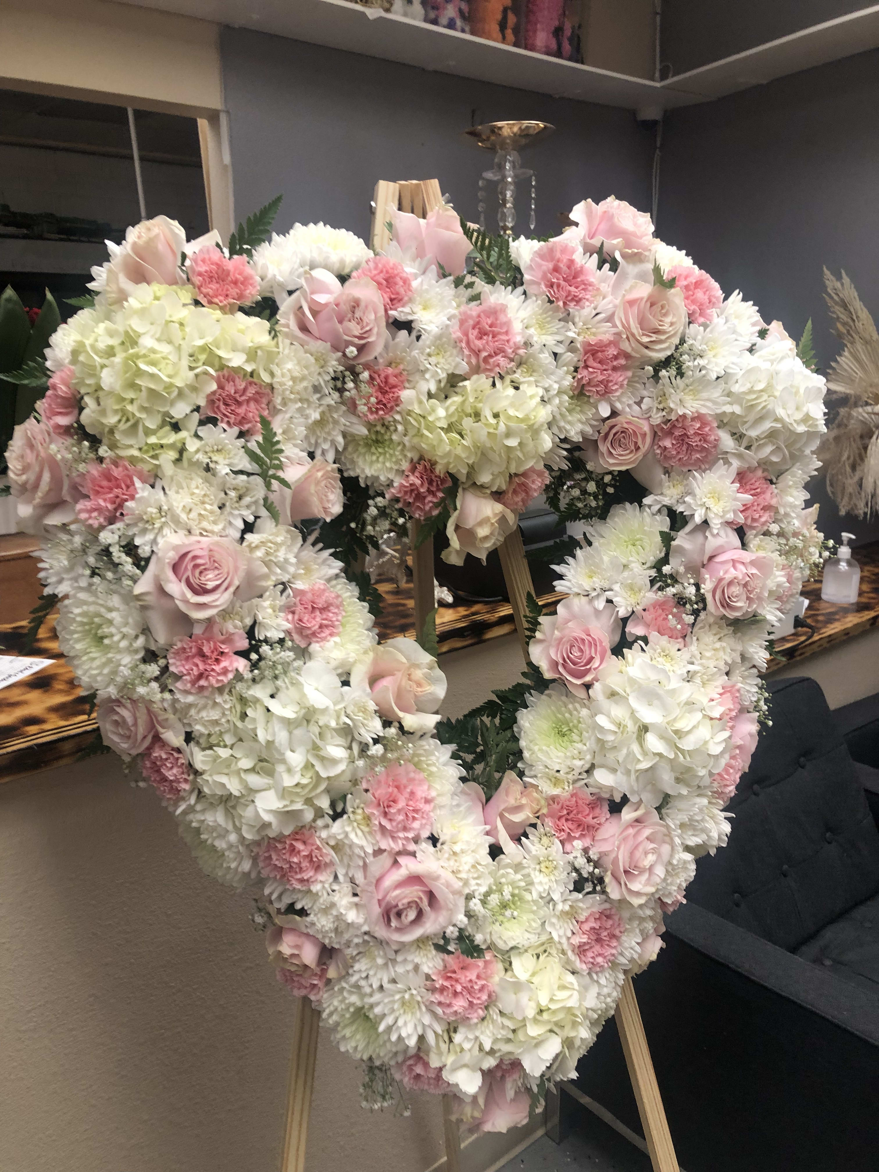 Heart-shaped floral arrangement with pink and white roses and carnations