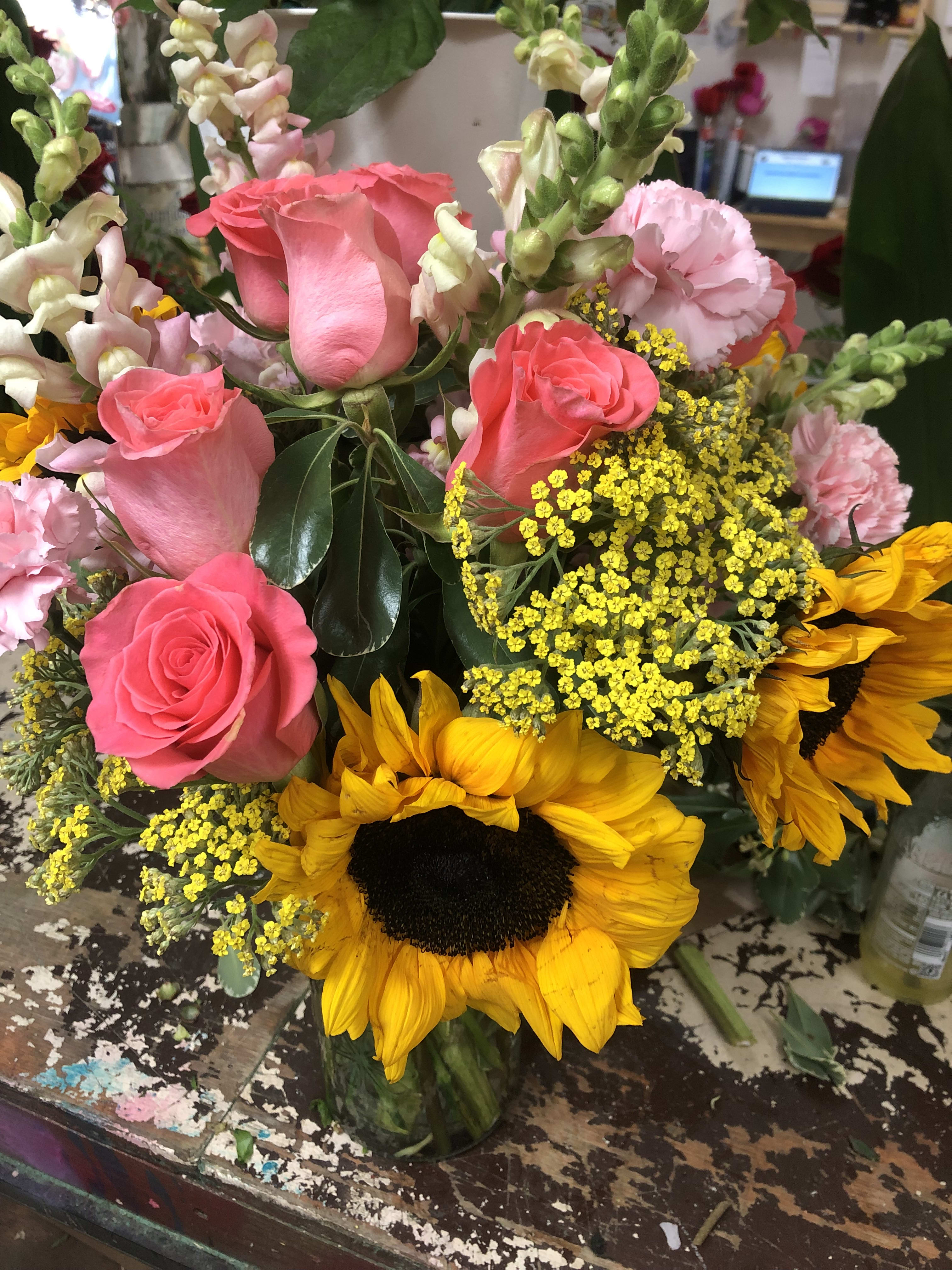 Bouquet of pink roses and yellow sunflowers in a glass vase