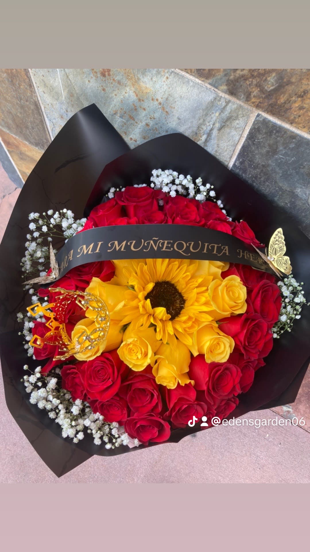 Bouquet of red and yellow roses with a sunflower and black wrap
