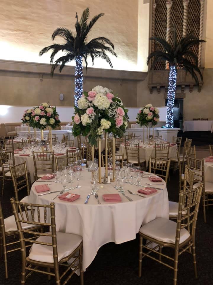 Tall floral centerpieces on round banquet tables in a reception hall
