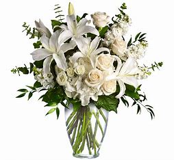White lilies and roses arranged in a clear glass vase