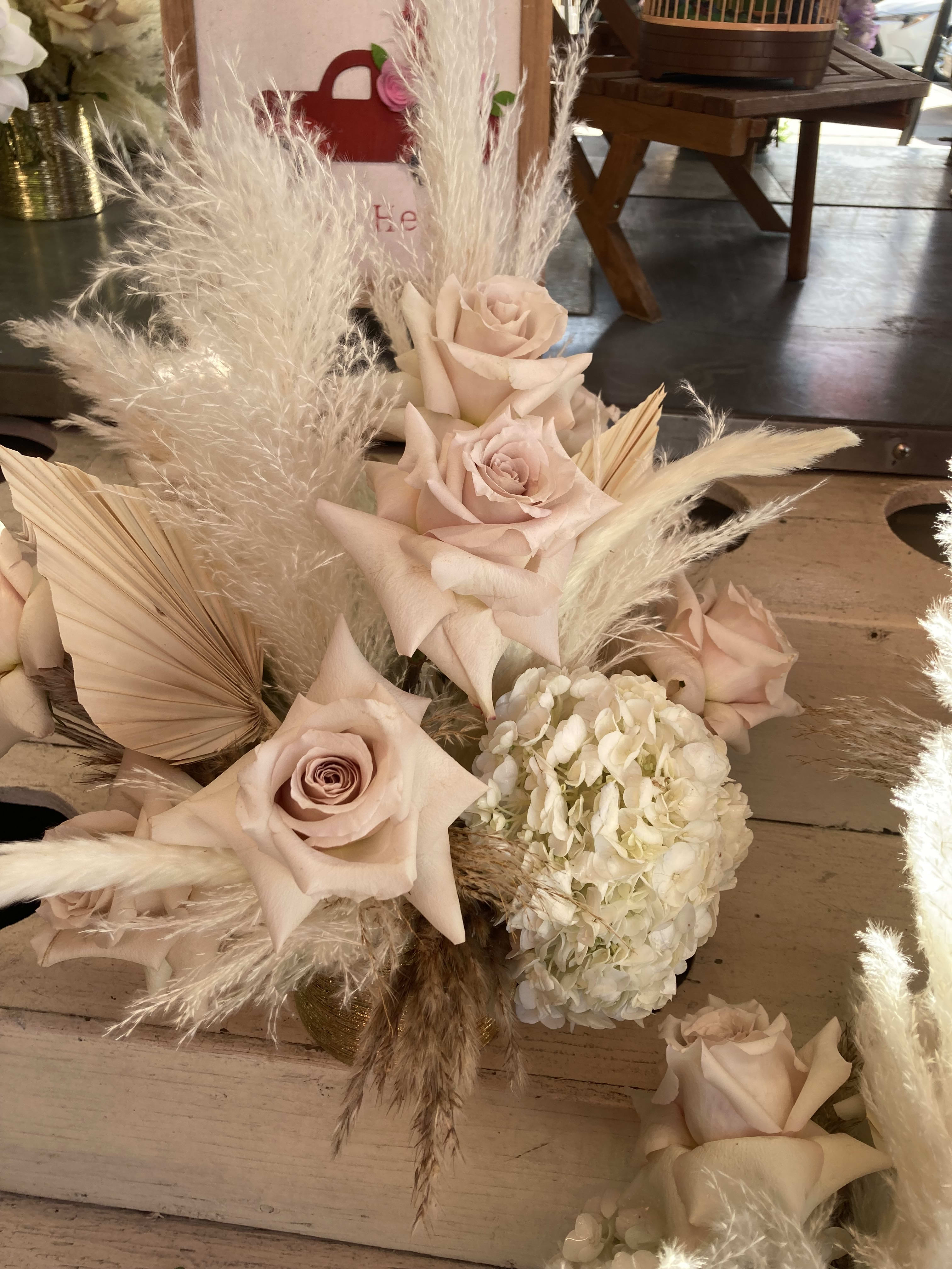 Blush roses and white hydrangea with tall pampas grass in a low arrangement