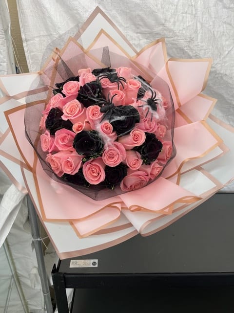 Bouquet of pink and black roses wrapped in pink paper