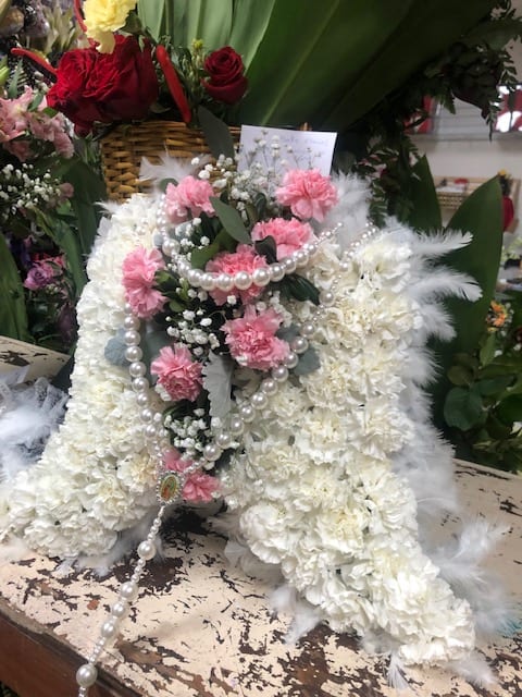 White floral funeral spray with pink carnations and pearl strands